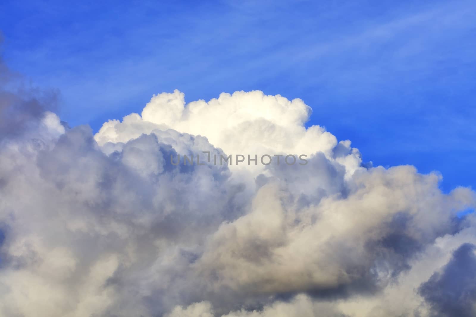 In the blue sky a white-gray fluffy cloud gradually takes up space.