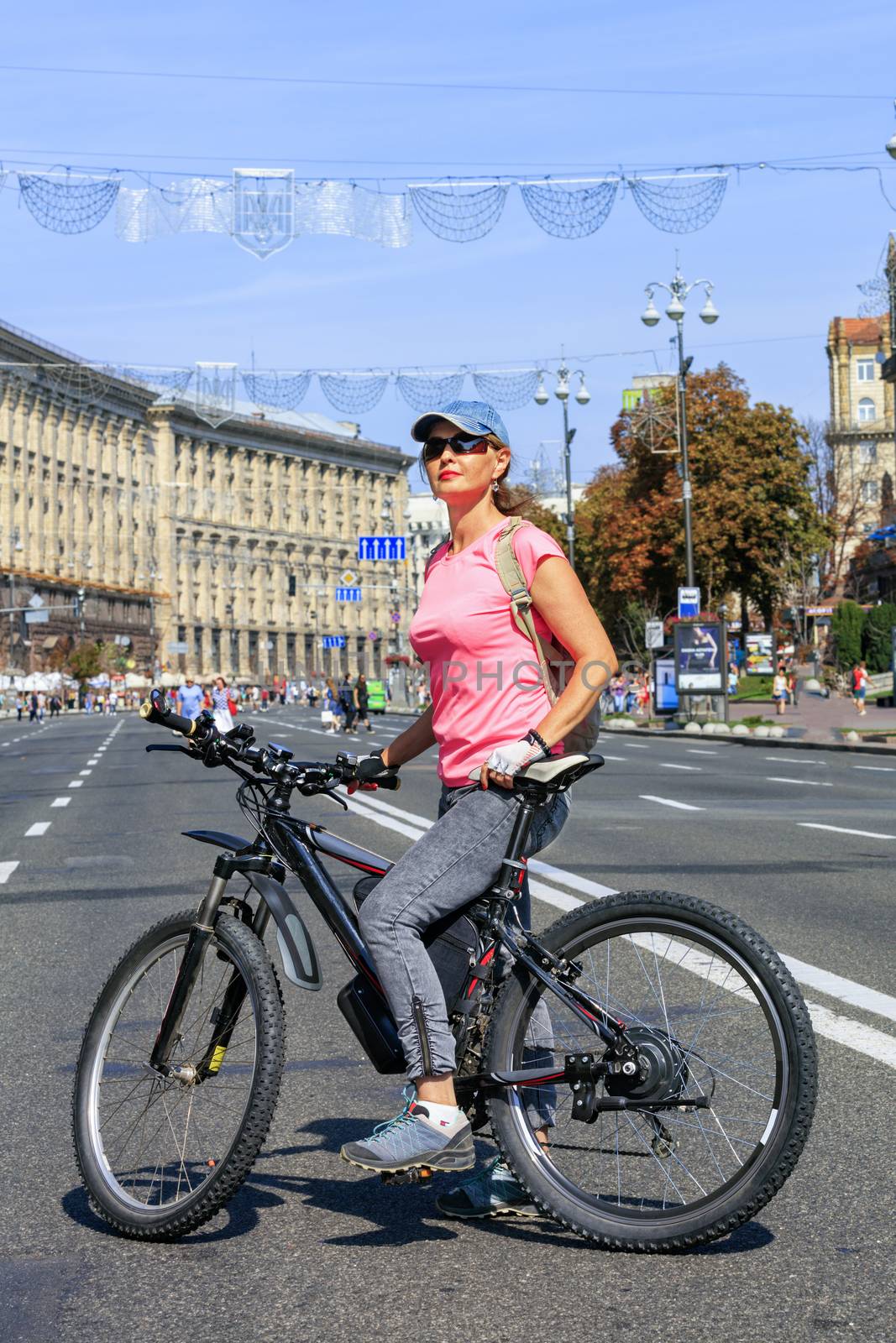 A young lady on a mountain electric bike stands on the road of Khreschatyk Street in Kyiv. by Sergii