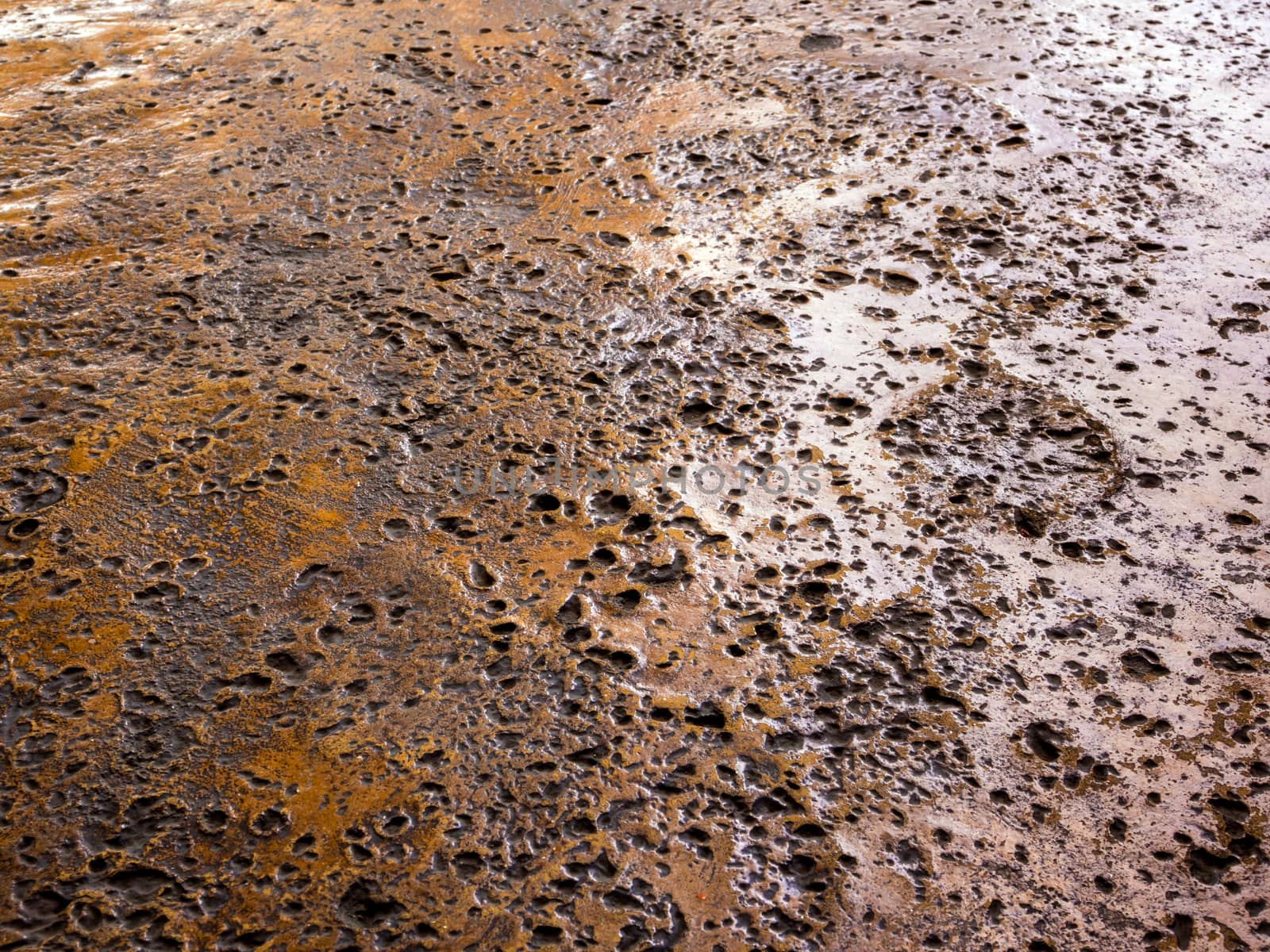 Many rugged holes on the rusty color concrete floor