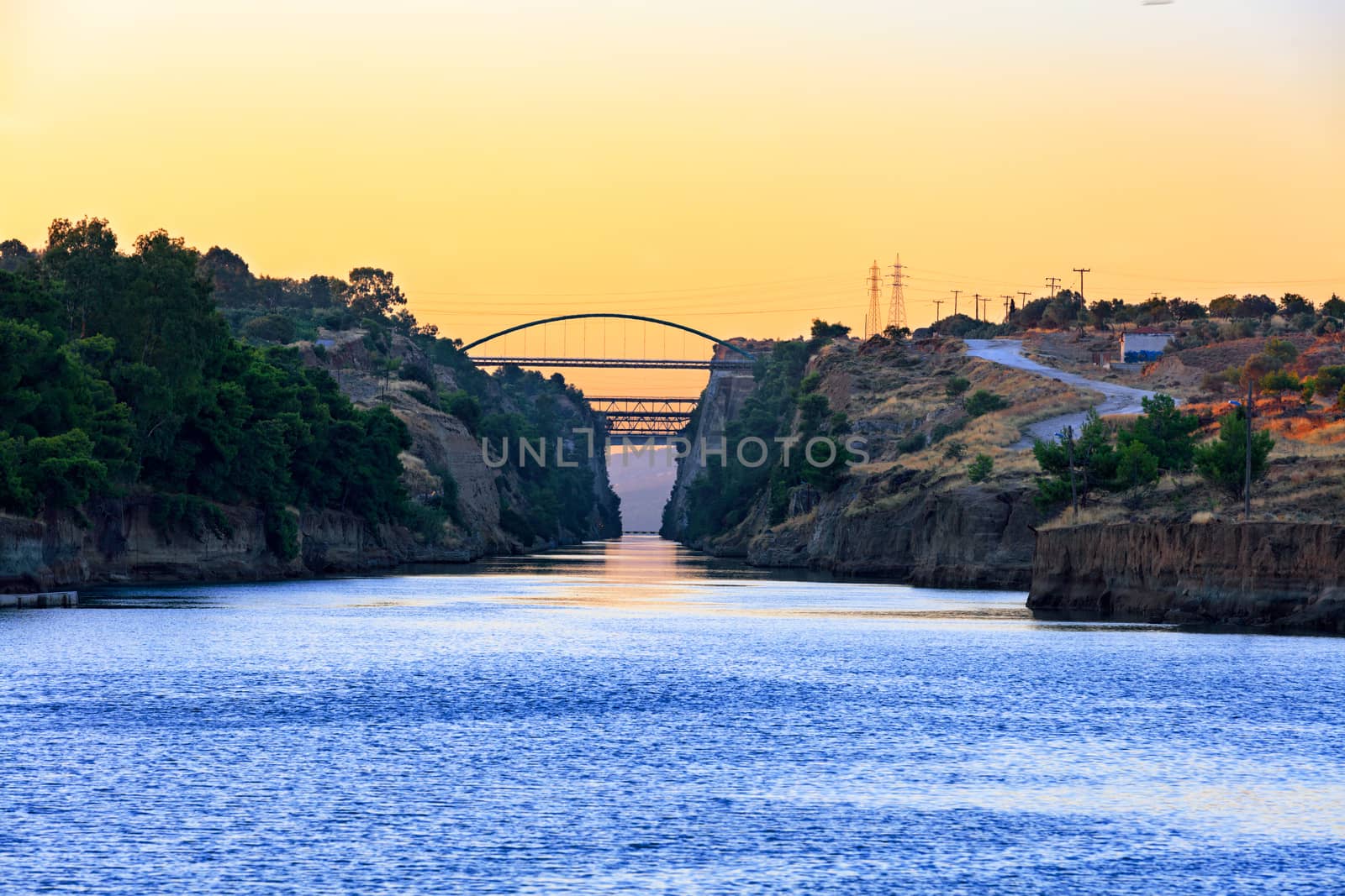 Wide entrance and view of transport bridges in the Corinth Canal in Greece in the rays of the rising sun and the horizon in the morning haze of the sea, image with copy space.
