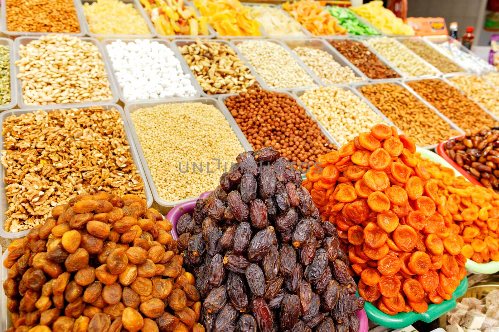Slides with dates, dried apricots, almonds, hazelnuts, walnuts, cashews in blur are sold on the shelves of the eastern market.