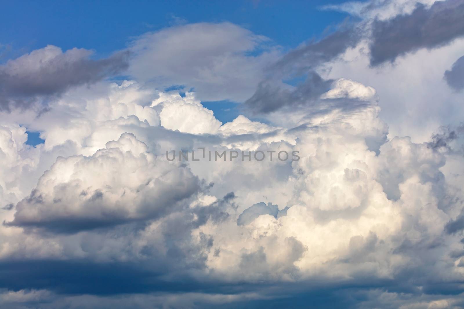 White-gray cumulus clouds gradually gather together into one continuous cover in anticipation of rain.