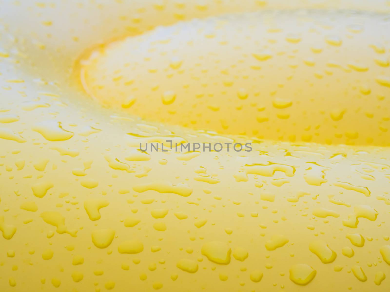 Water droplet on surface of vivid yellow pool float balloon