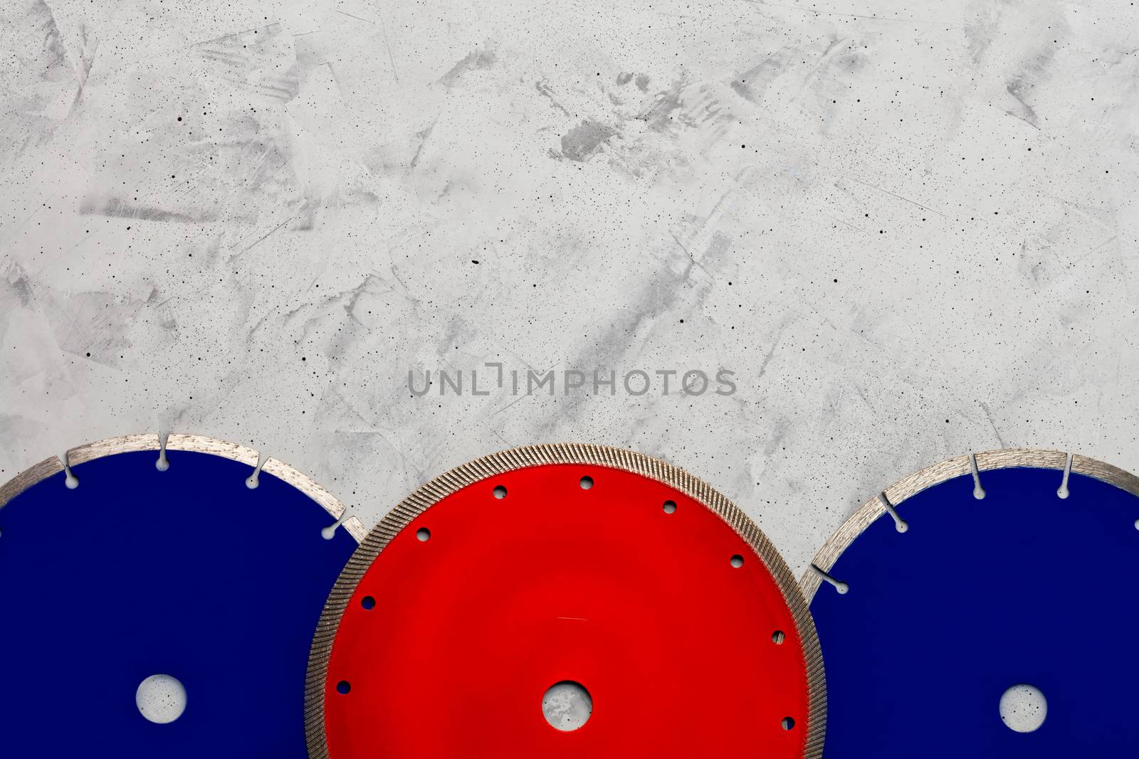 Cutting discs blue and red color with diamond for cutting concrete, reinforced concrete and granite on a gray concrete background, image with copy space.