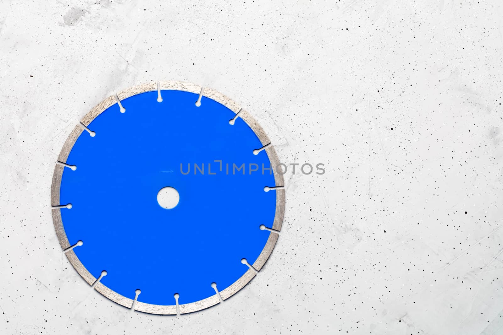 Cutting blade blue color with diamond for cutting reinforced concrete using an angle grinder on a gray concrete background, image with copy space.