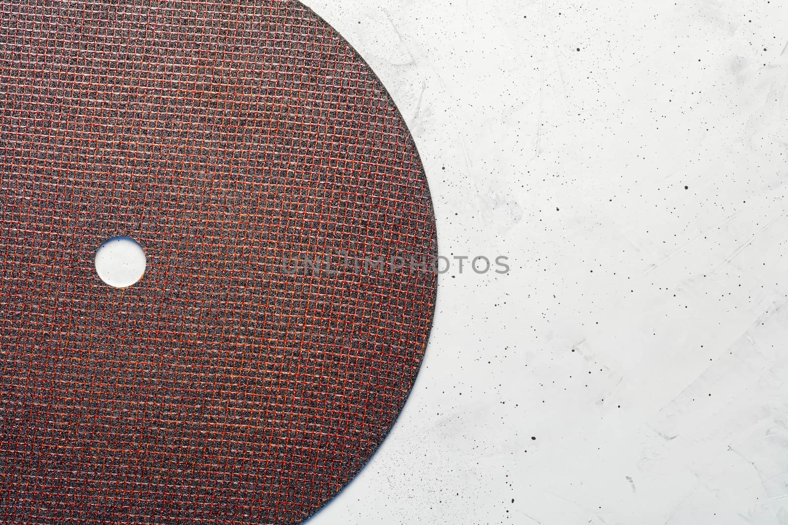 Segment semicircle of abrasive disc on a background of gray concrete close-up, image with copy space.