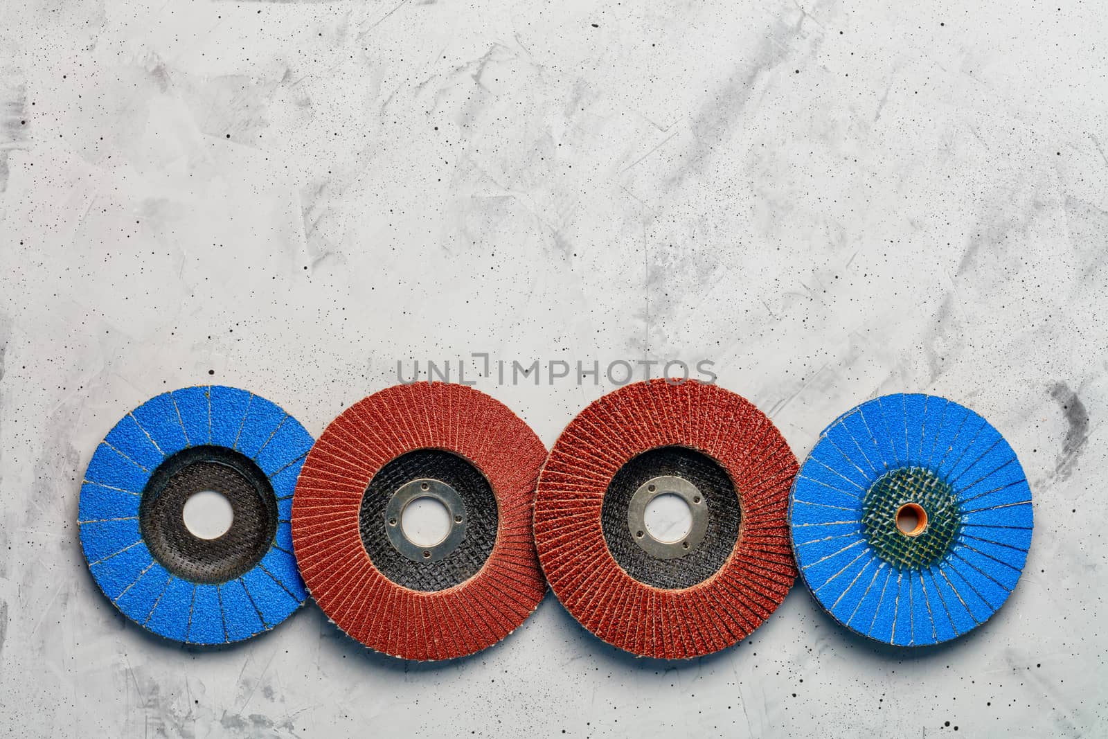 Set of grinding abrasive emery discs for grinding of the metal, wood and stone on the gray concrete background, close-up, image with copy space.