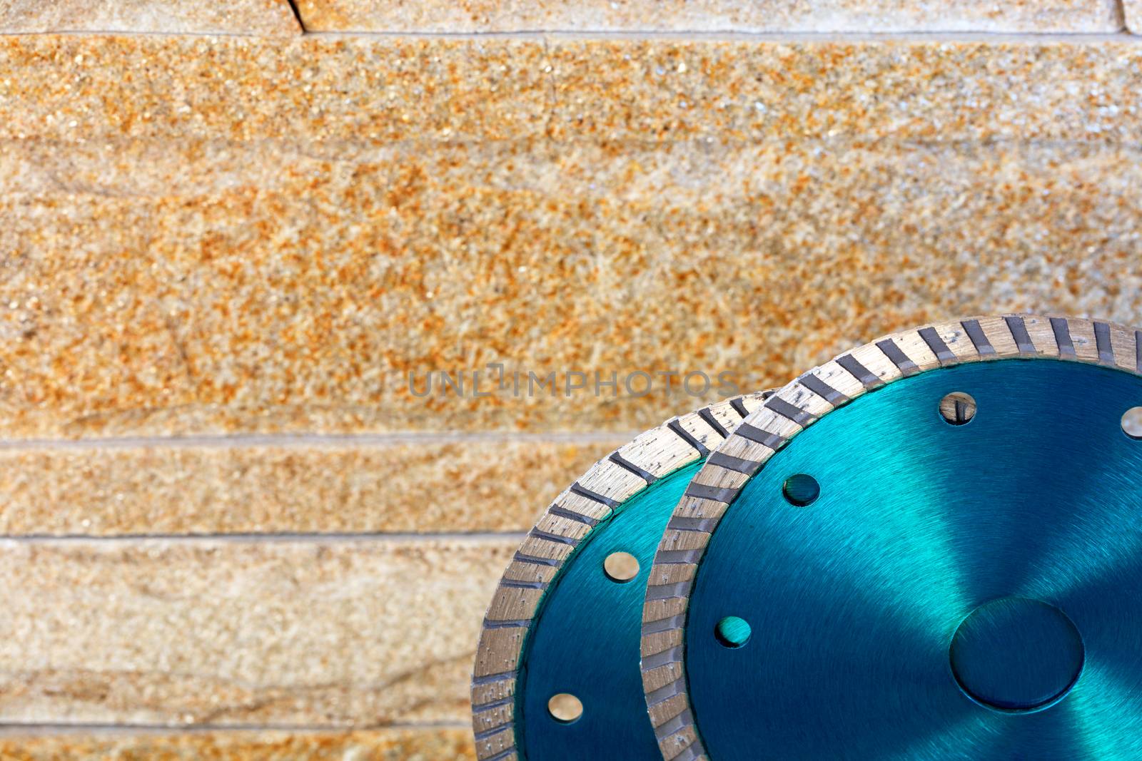 Cutting discs green color with diamond for cutting stone, sandstone and granite on a background of golden sandstone in blur, image with copy space.
