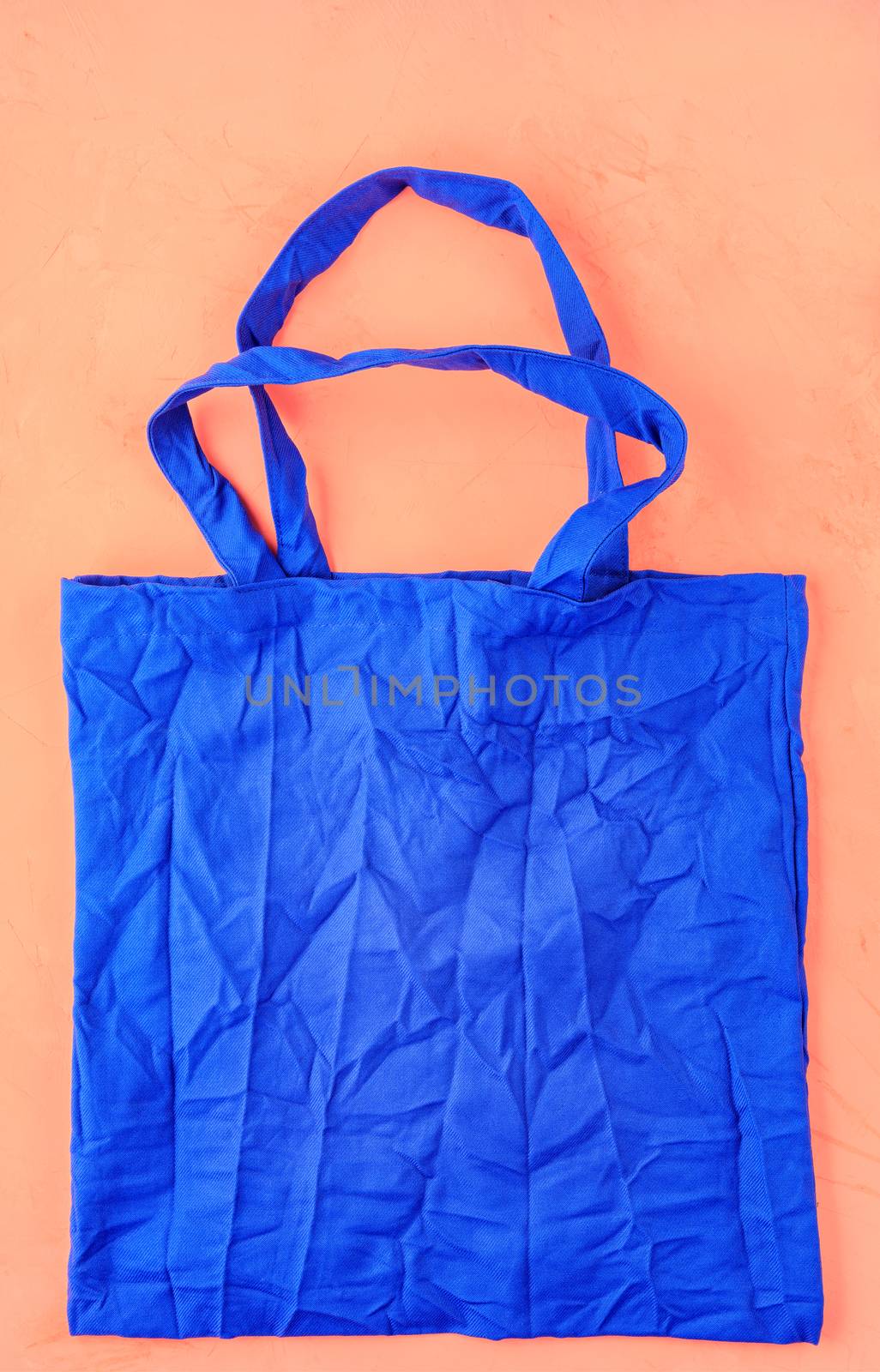 Eco-friendly cotton bag in classic blue color against a peach color background. Zero waste concept, plastic-free, eco-friendly shopping.
