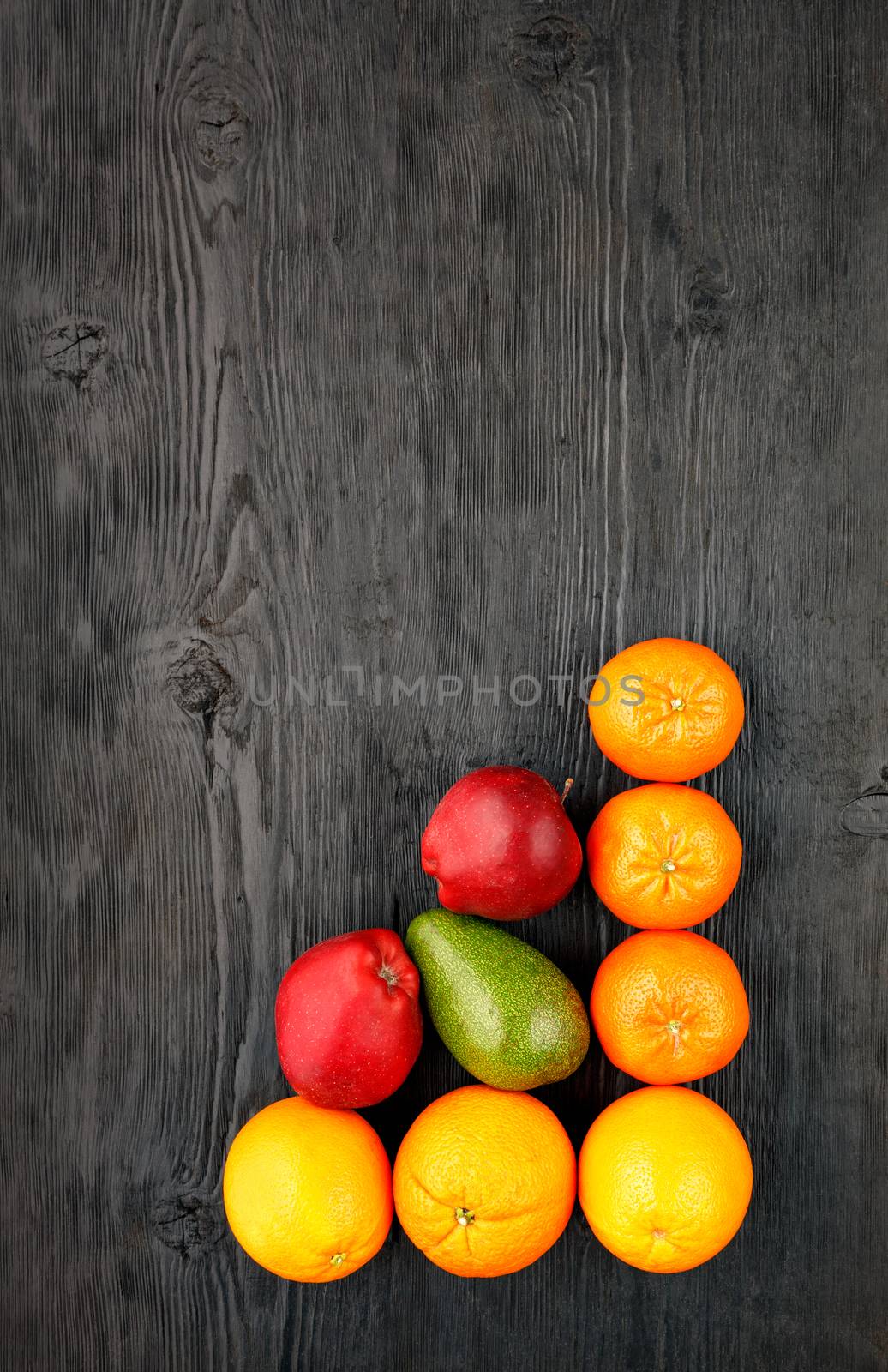 Ripe fruits and citrus fruits lie on an old black wooden table. by Sergii