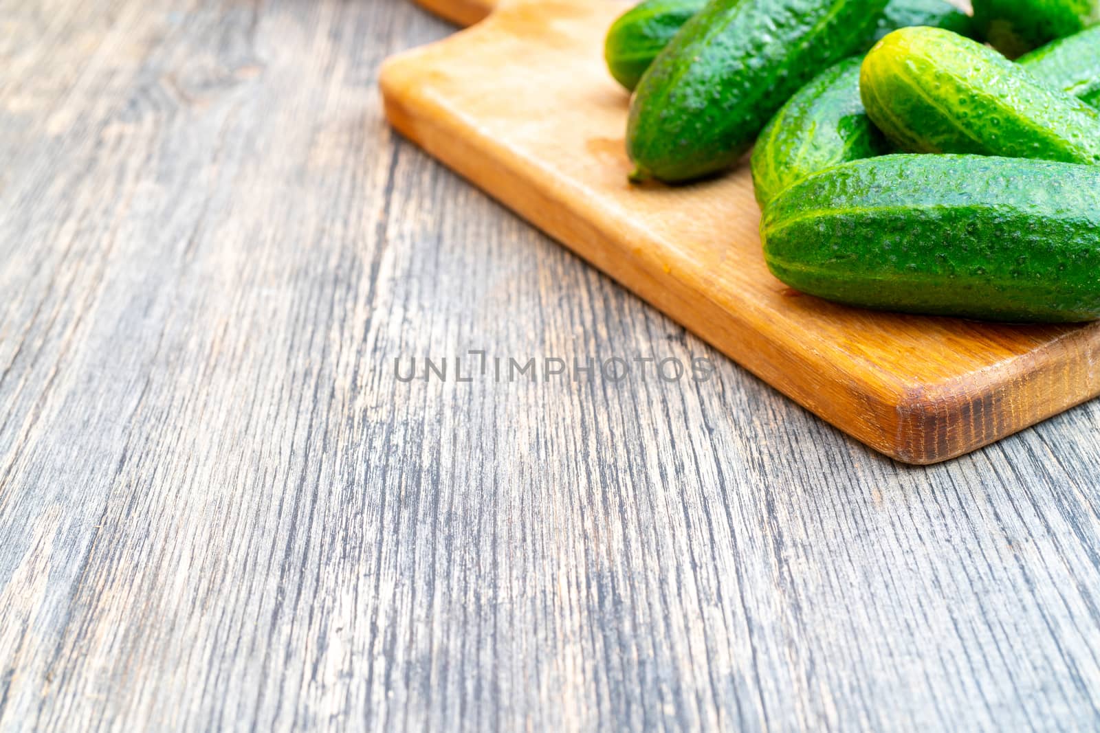 Ripe green cucumbers on cutting board for vegetables. Vegetables on kitchen table.