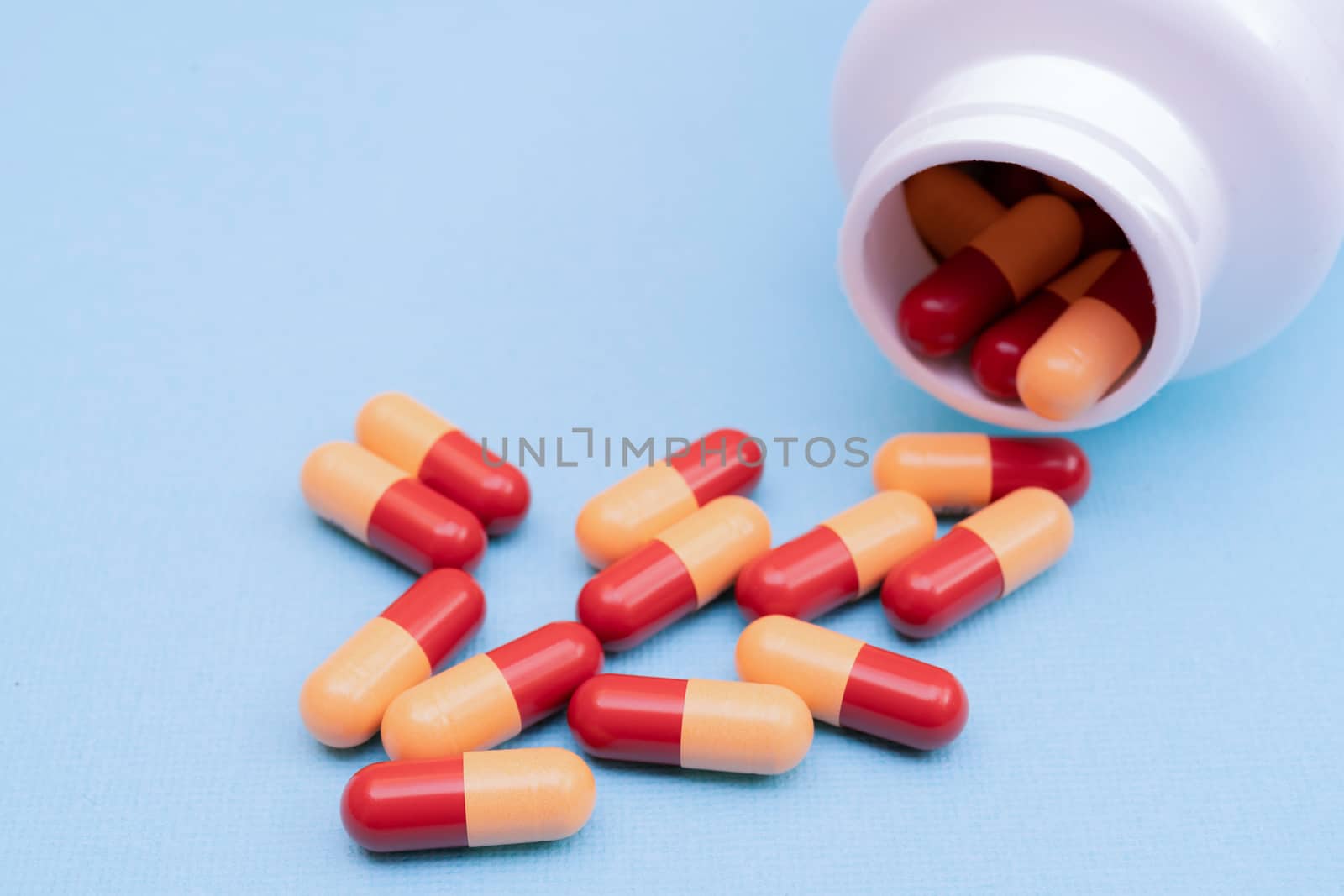 Medicine pills or capsules on blue background with copy space. Medicinal prescription for drug treatment. Pharmaceutical drug, medicine in container for health. Sale of antibiotic in pharmacy.