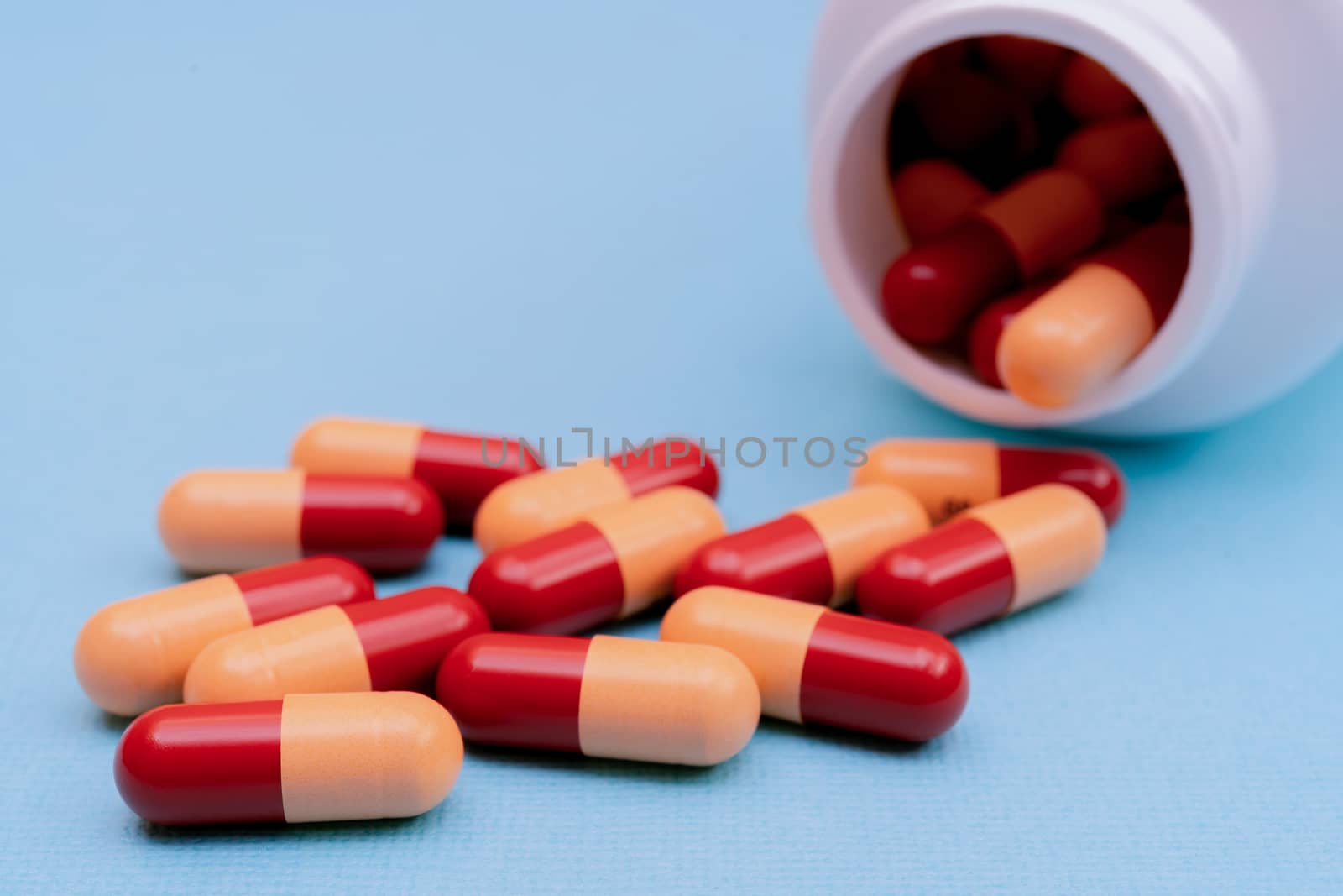 Medicine pills or capsules on blue background with copy space. Medicinal prescription for drug treatment. Pharmaceutical drug, medicine in container for health. Sale of antibiotic in pharmacy.