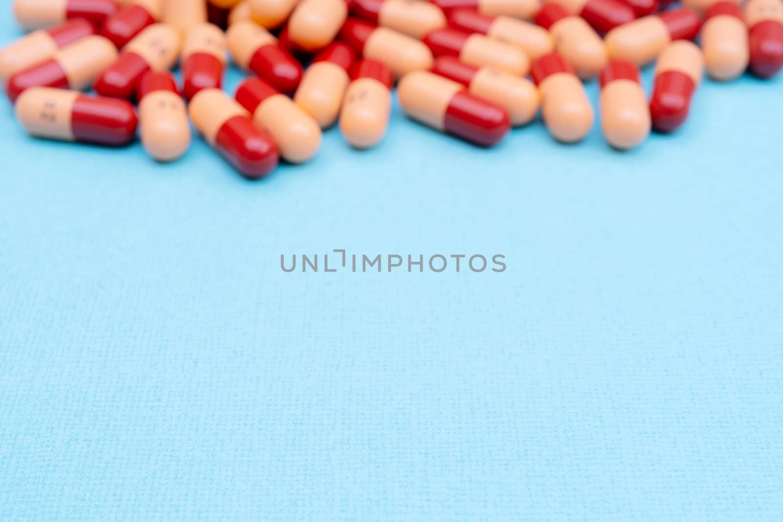Medicine pills or capsules on blue background with copy space. Medicinal prescription for drug treatment. Pharmaceutical drug, medicine in container for health. Sale of antibiotic in pharmacy.