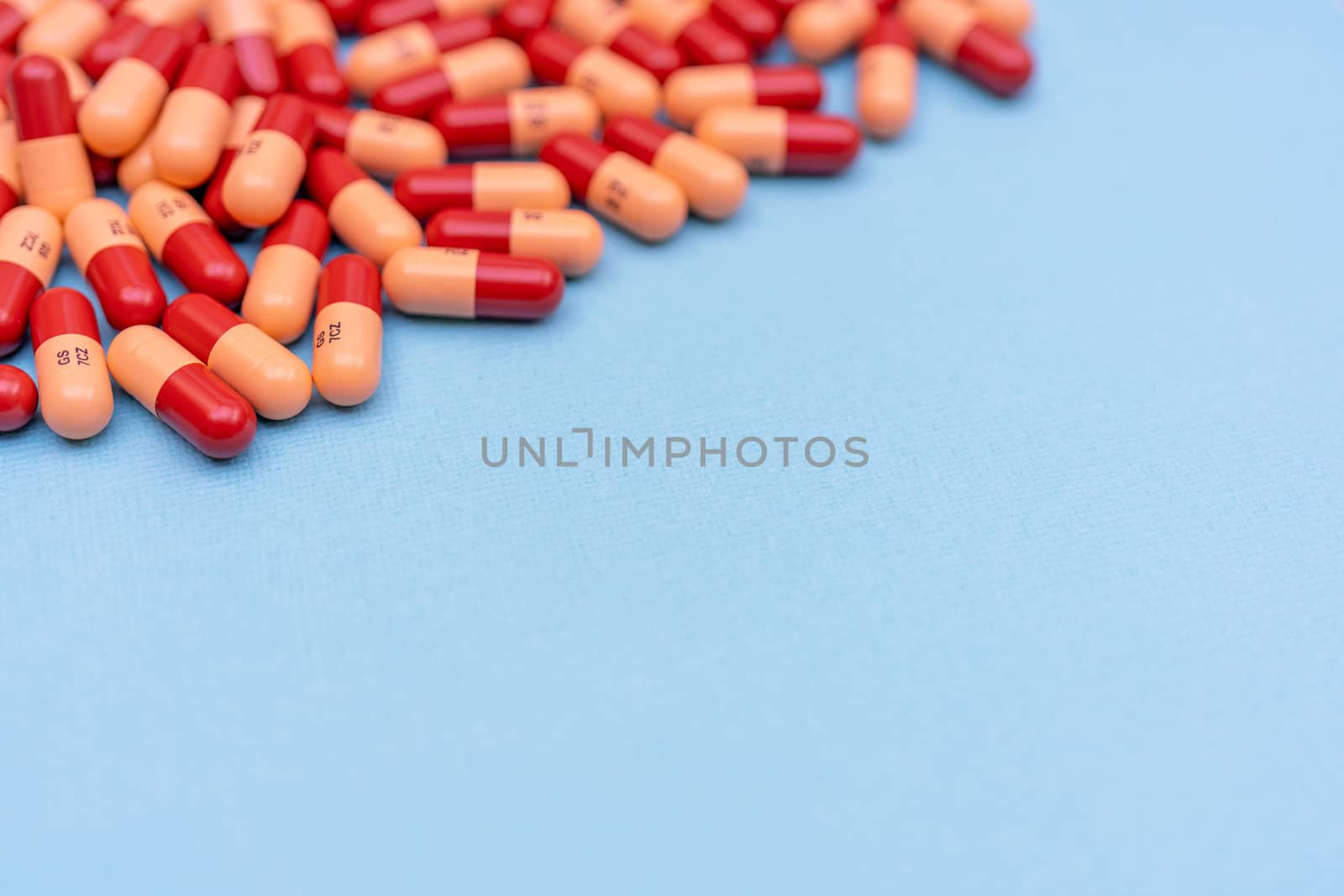 Medicine pills or capsules on blue background with copy space. Medicinal prescription for drug treatment. Pharmaceutical drug, medicine in container for health. Sale of antibiotic in pharmacy.