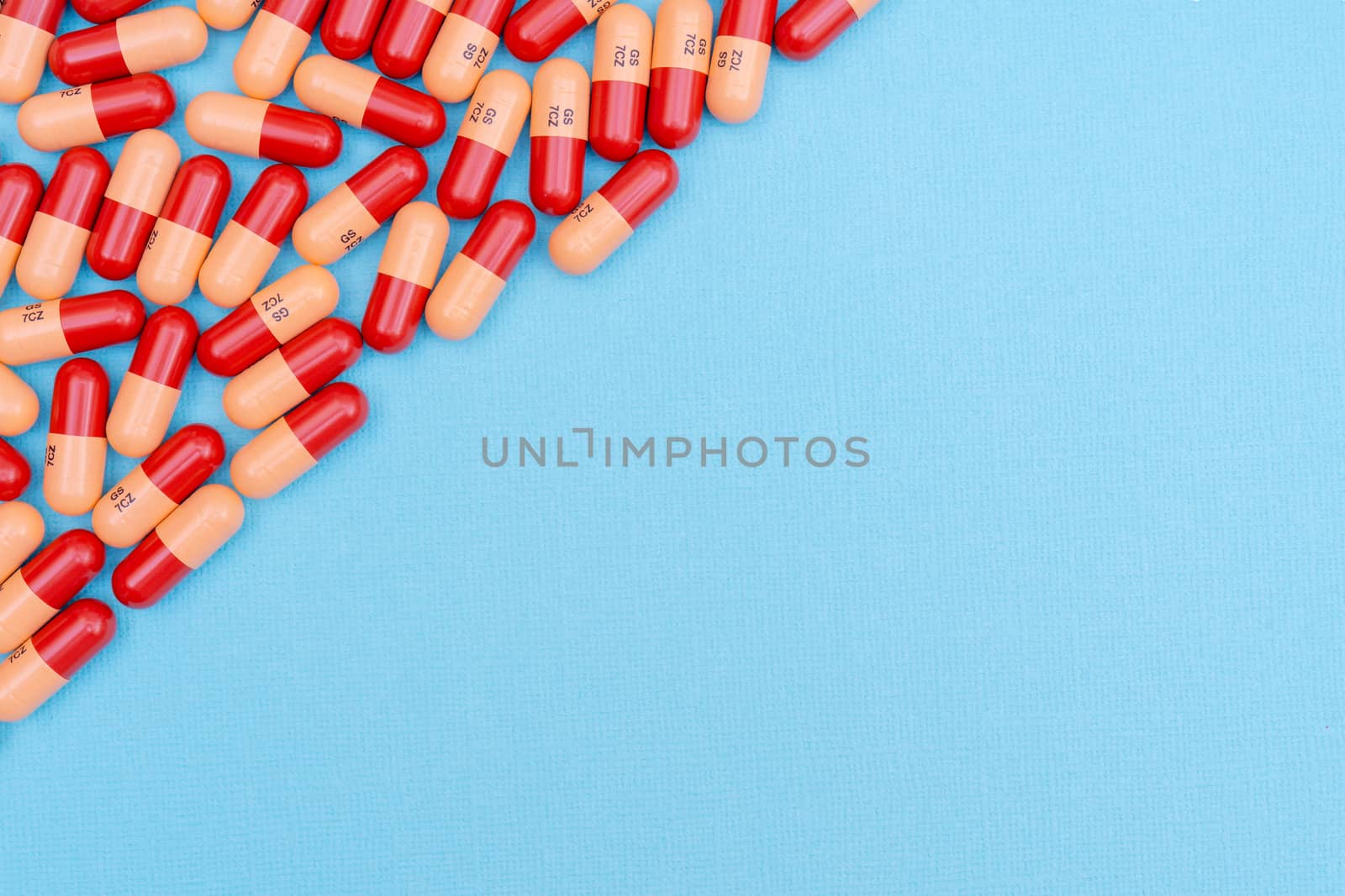 Medicine pills or capsules on blue background with copy space. Medicinal prescription for drug treatment. Pharmaceutical drug, medicine in container for health. Sale of antibiotic in pharmacy.