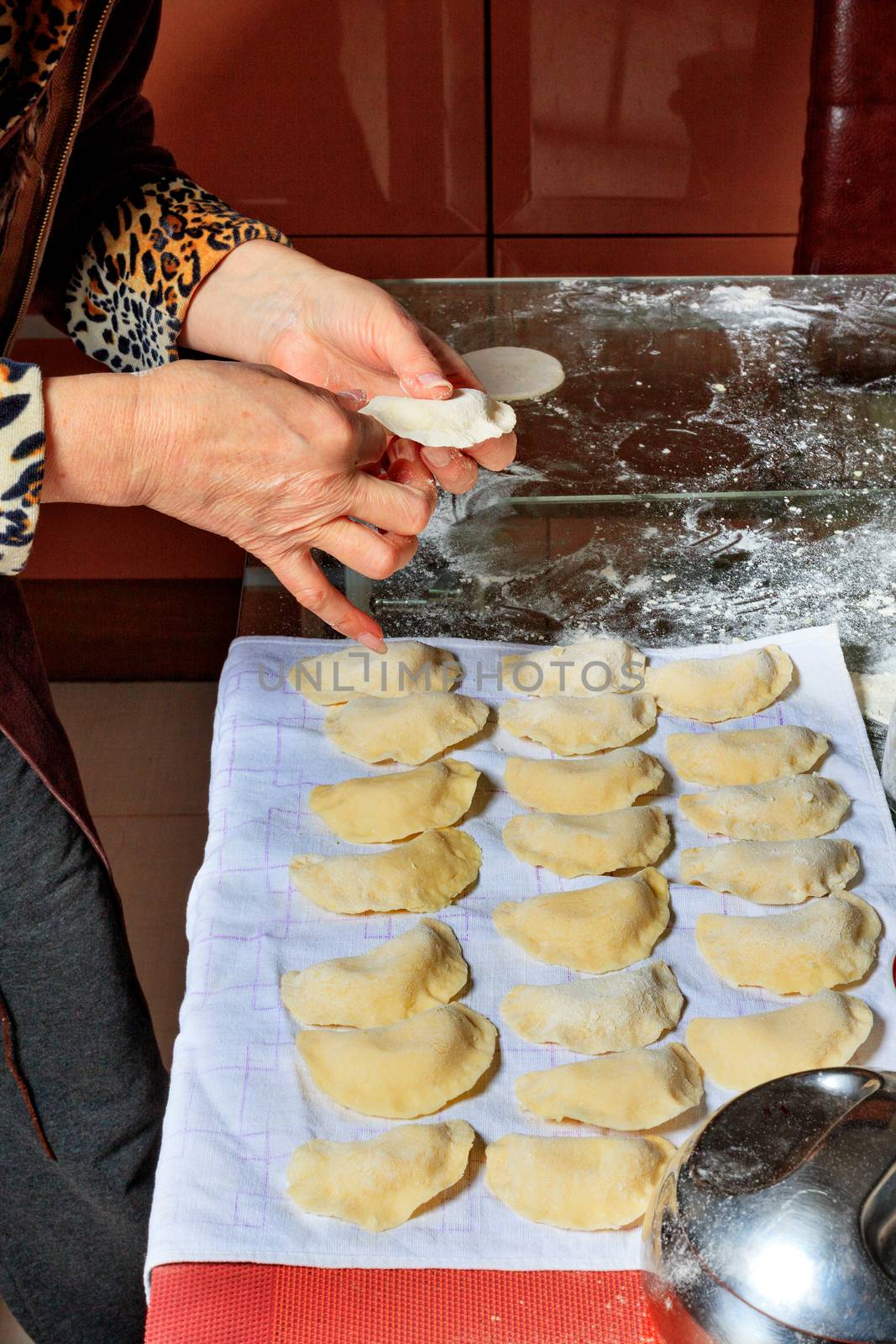 Woman spreads the finished raw dumplings on a tissue napkin. by Sergii