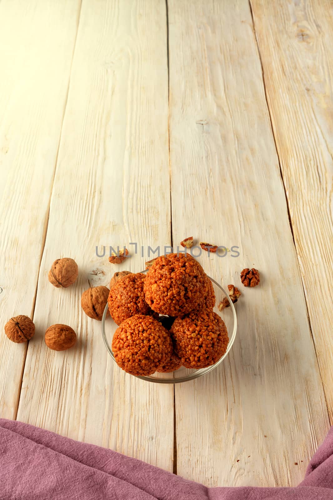 Homemade energy balls with walnuts, peanut, honey and banana on a light wooden surface, top view, vertical image. by Sergii