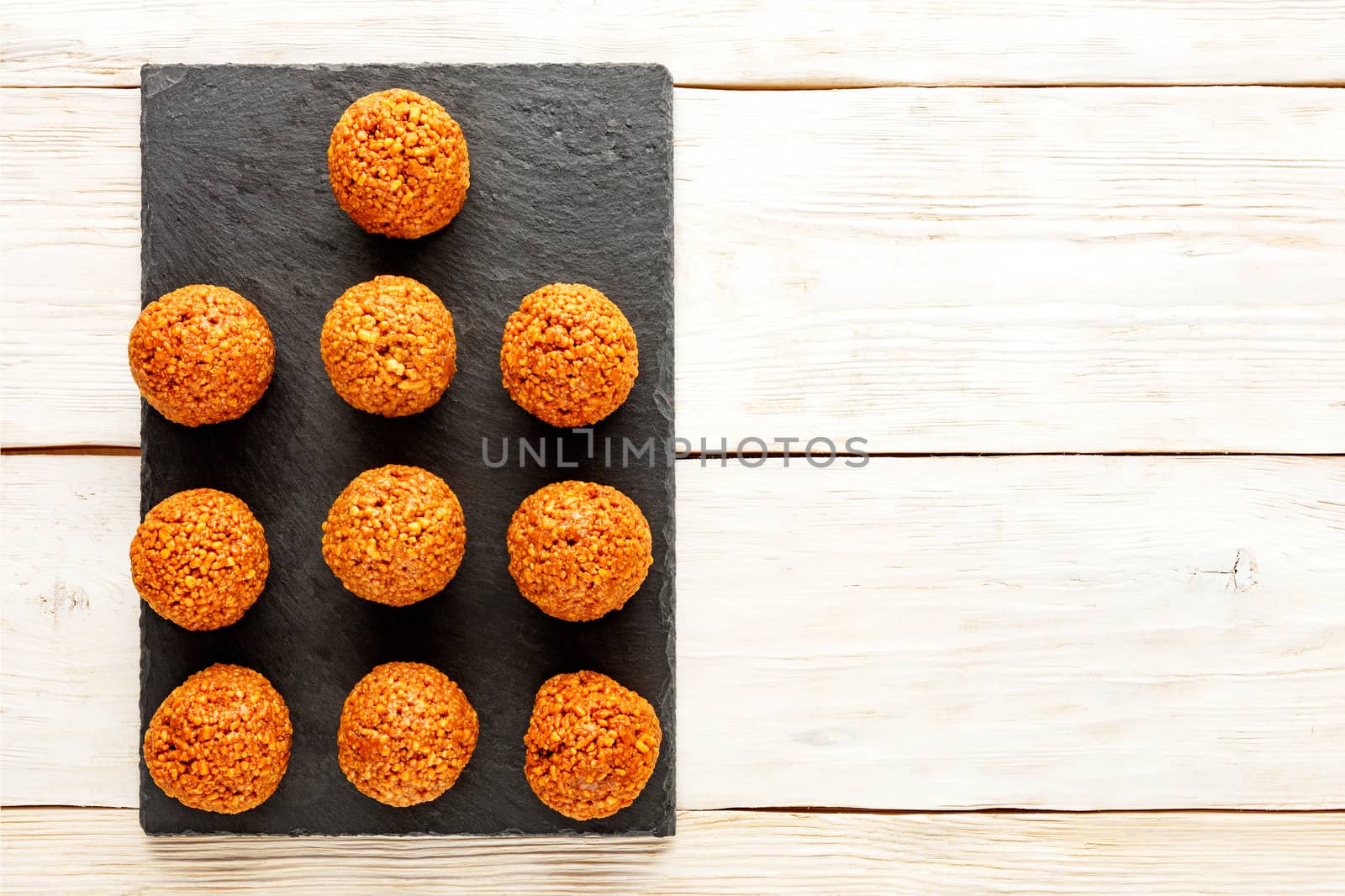 Homemade energy balls with walnuts, peanut, honey and banana on a light wooden table background. Vegan Vegetarian Raw Snacks. Healthy Sweet Food. Copy space. Flat lay, top view.
