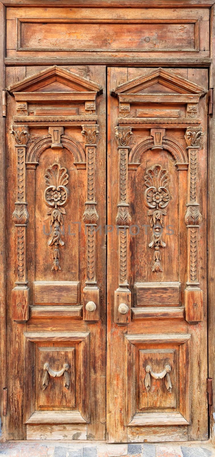 Old weathered wooden entrance doors with carved elements and a symmetrical pattern on the wings in the Ukrainian style. by Sergii