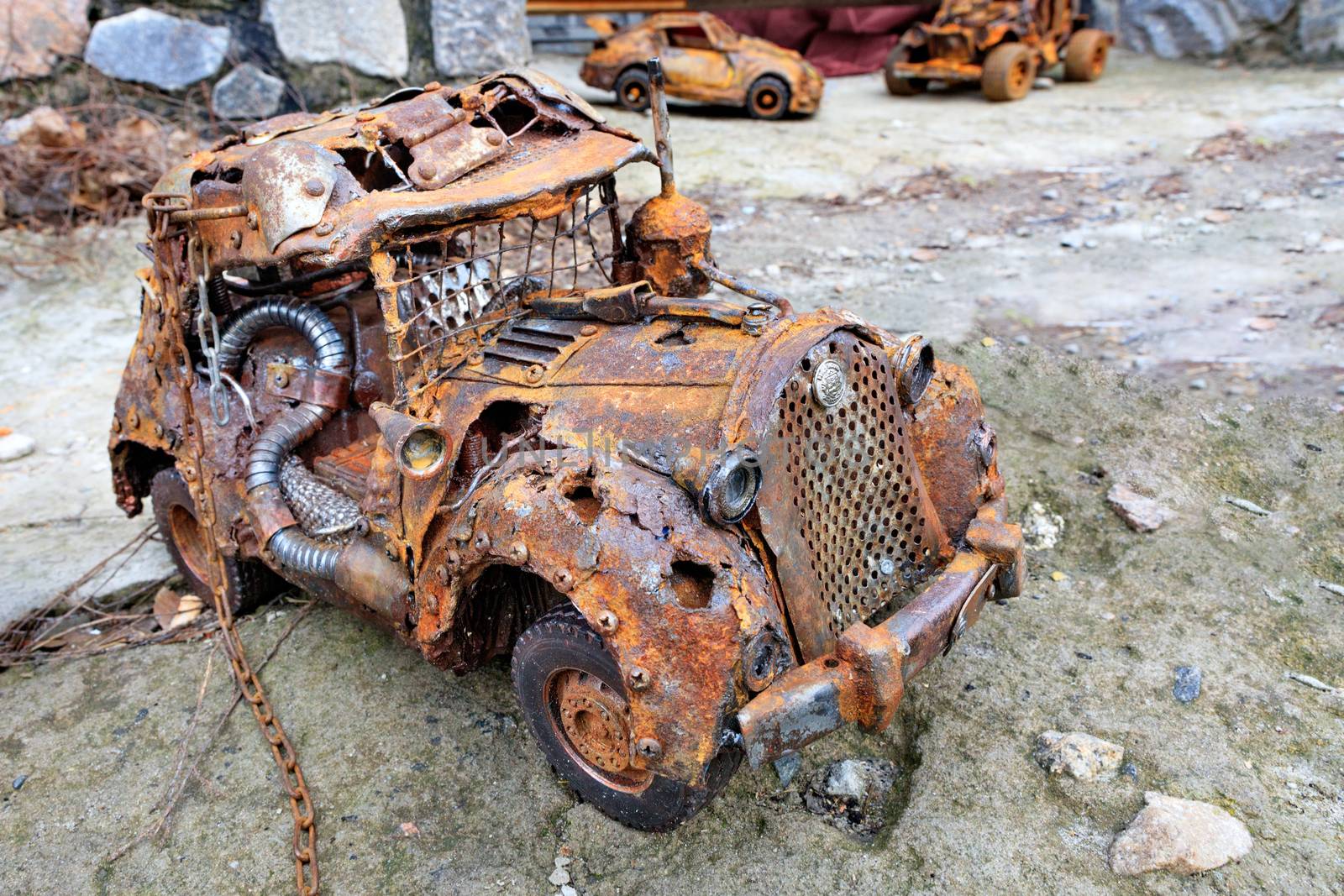 Rusty toy car with a chain made of household waste. by Sergii