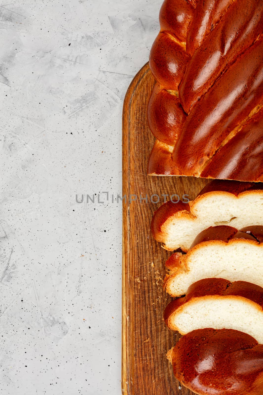 Fresh wicker sweet roll, homemade kalach ruddy on gray concrete background. Top view, copy space.