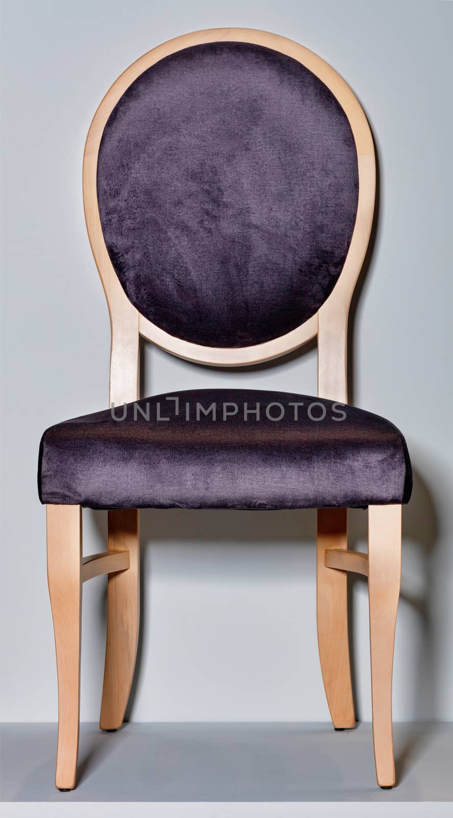 Wooden chair with a soft saddle and a round back on a gray podium and background. by Sergii