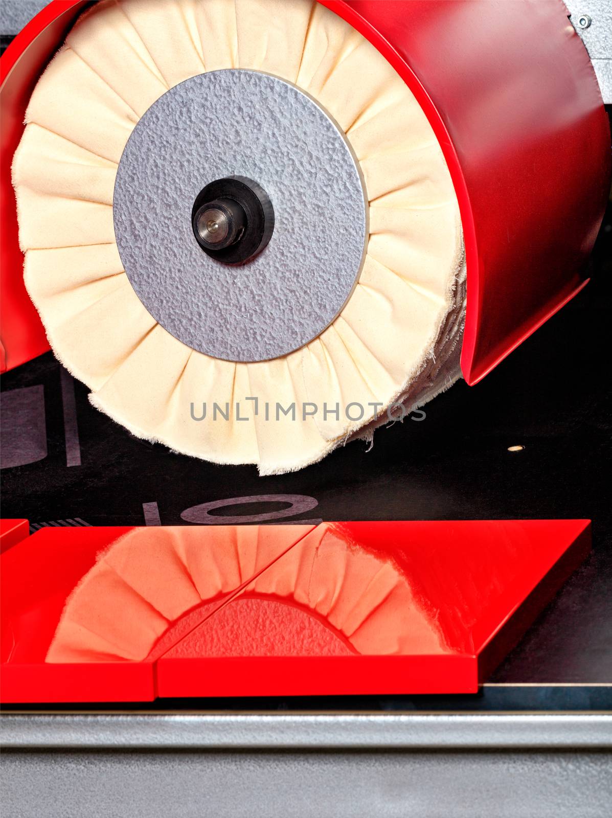 Modern disk polishing machine bright red for finishing grinding and polishing the facade of furniture plates and structures to mirror reflection, close-up.