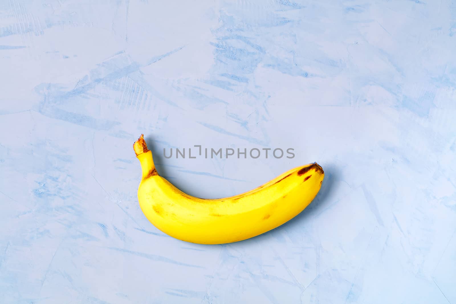 Yellow ripe banana on a dark blue concrete background, flat lay, image with copy space.