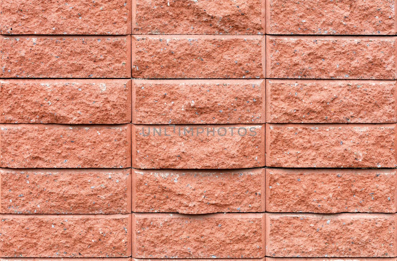 Wall texture of brown brick tiles with gray, beige and yellow granite splashes.