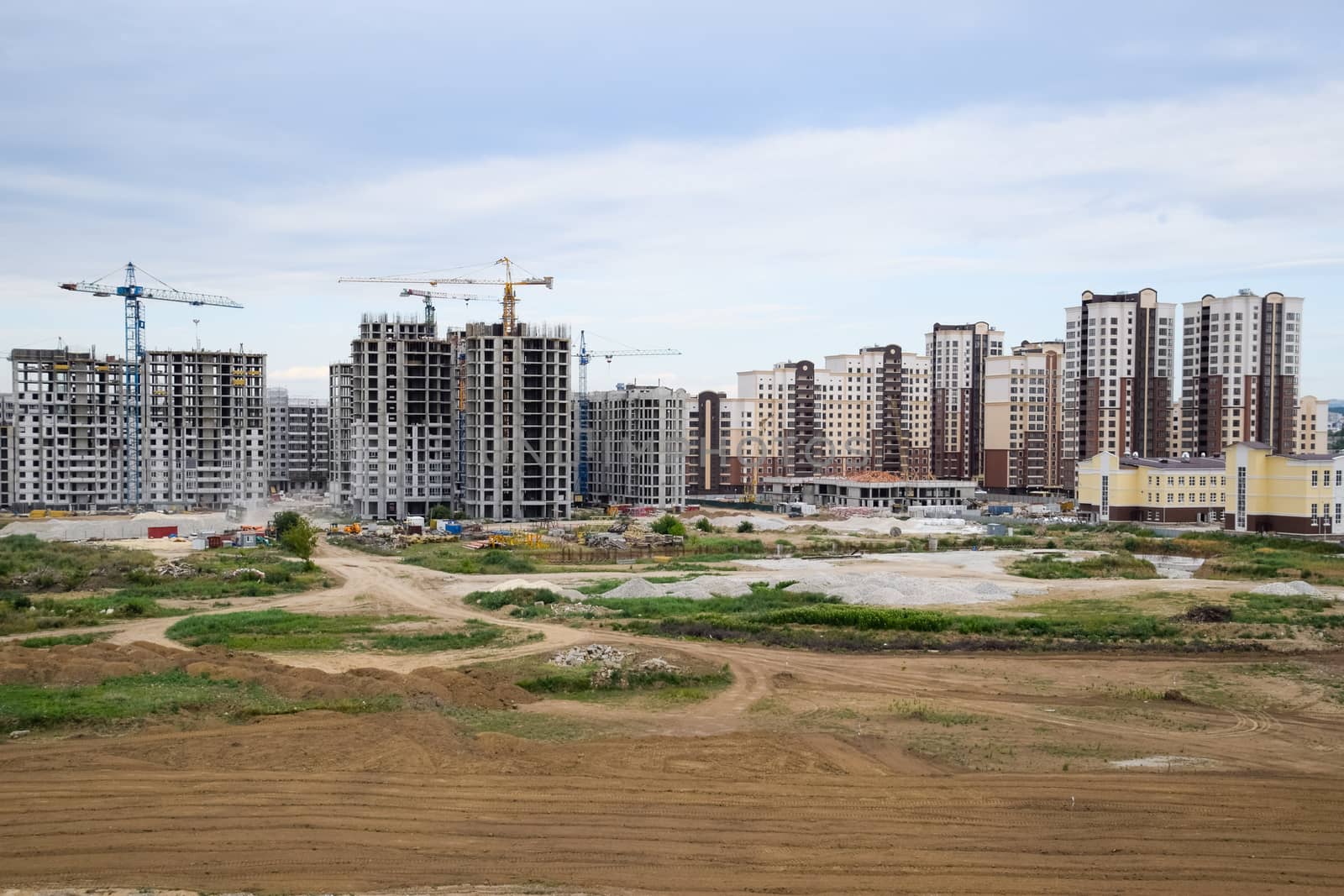 The construction of multi-storey residential buildings. Tower cranes at a construction site.