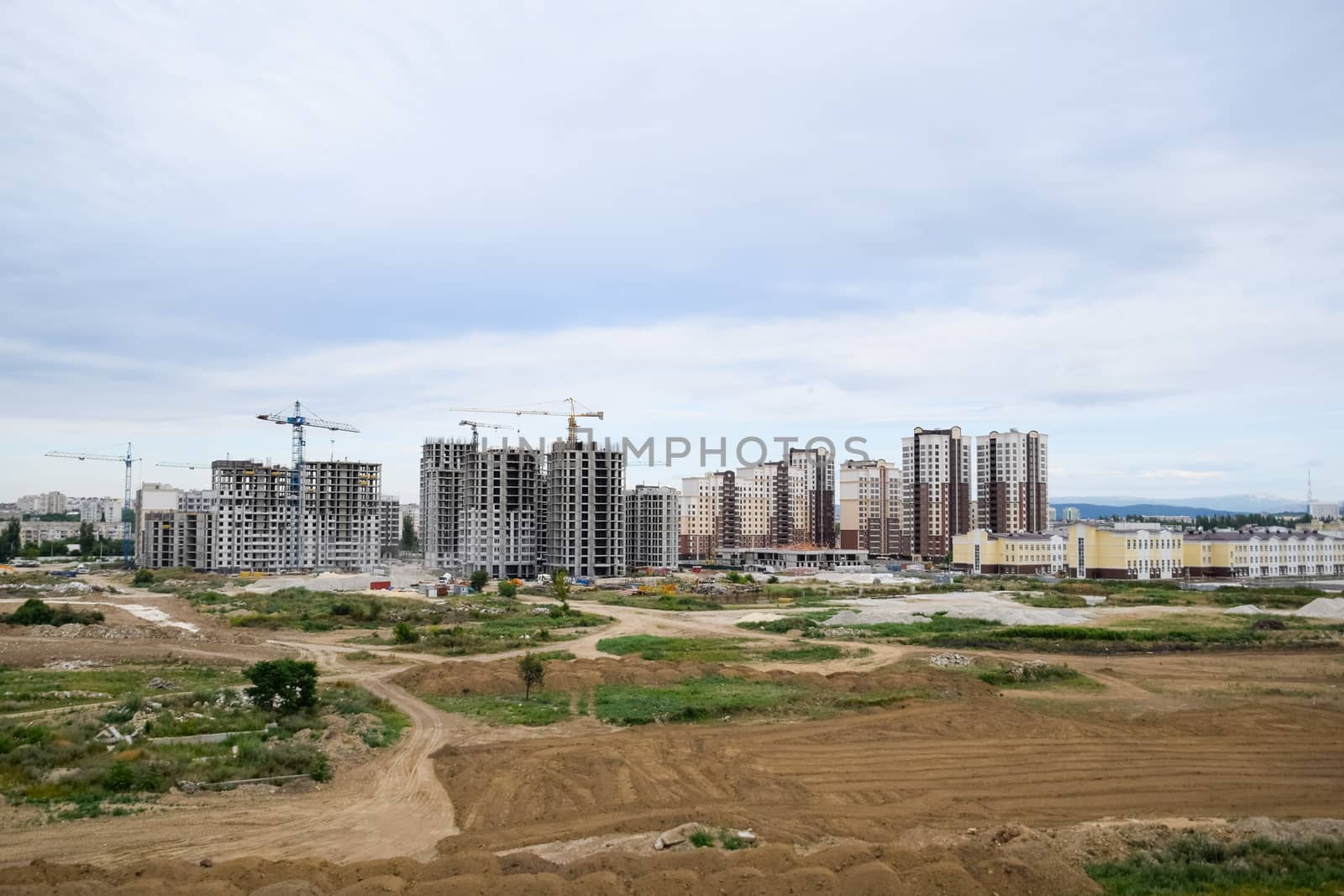 The construction of multi-storey residential buildings. Tower cranes at a construction site.