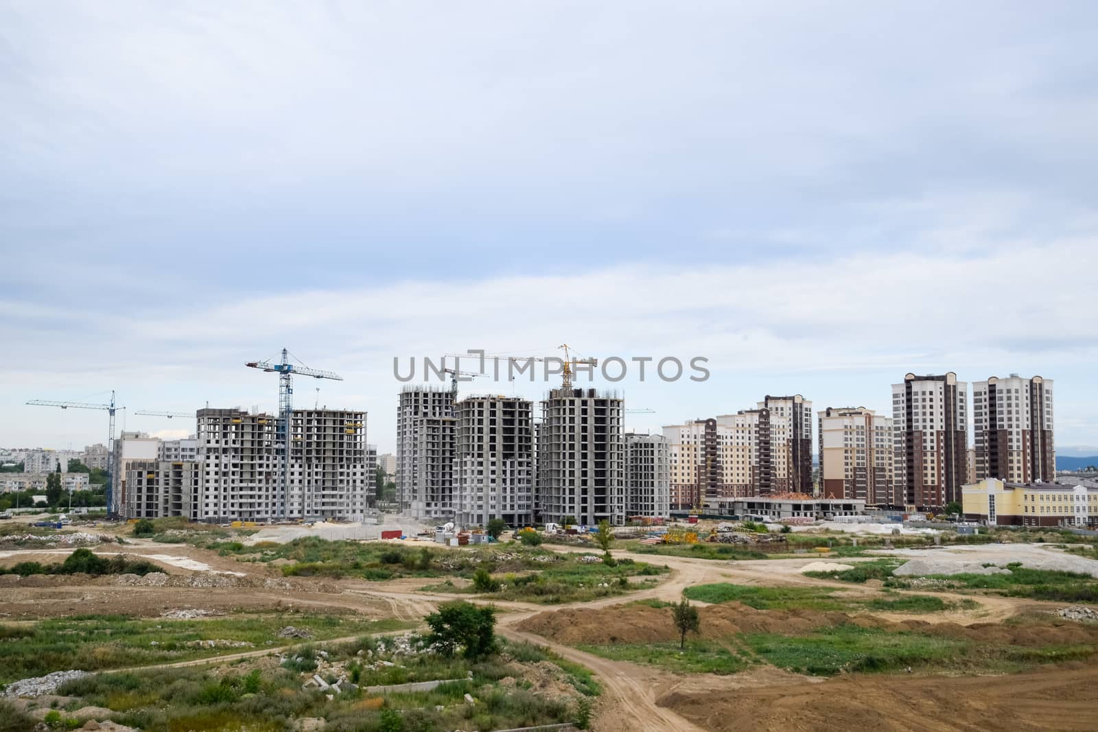 The construction of multi-storey residential buildings. Tower cranes at a construction site.