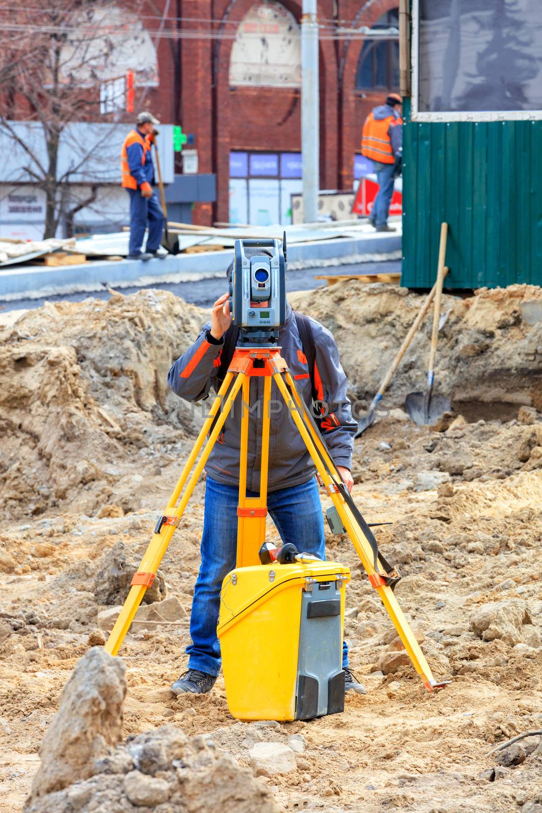 A road service engineer uses a laser level at a construction site. by Sergii