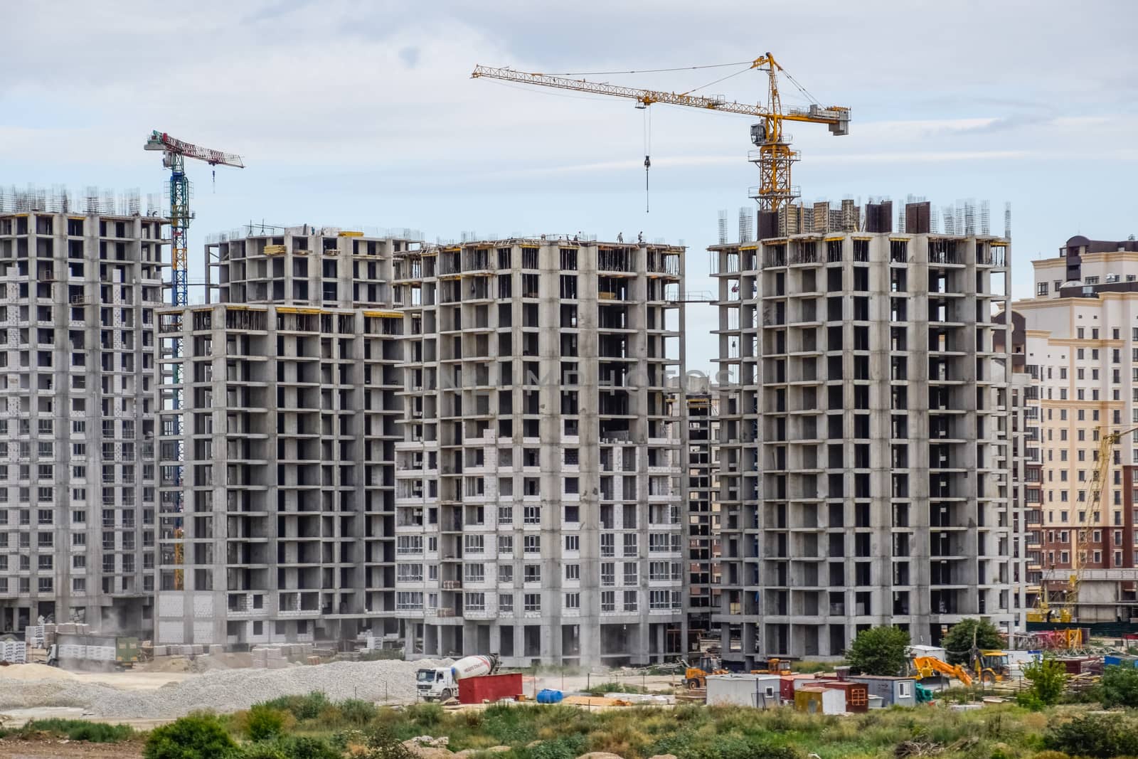 The construction of multi-storey residential buildings. Tower cranes at a construction site.