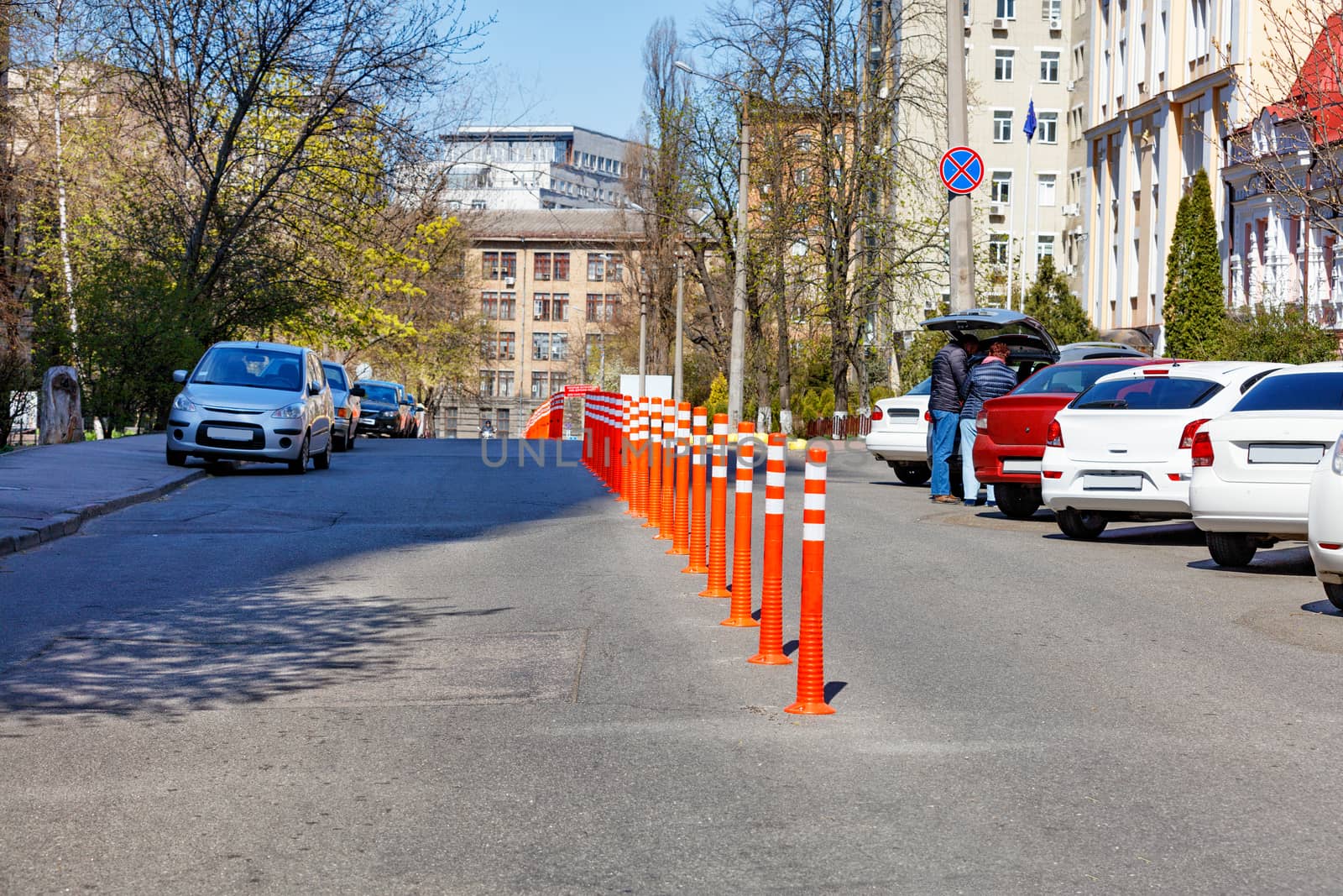Orange road columns bisect the carriageway in spring sunny day. by Sergii