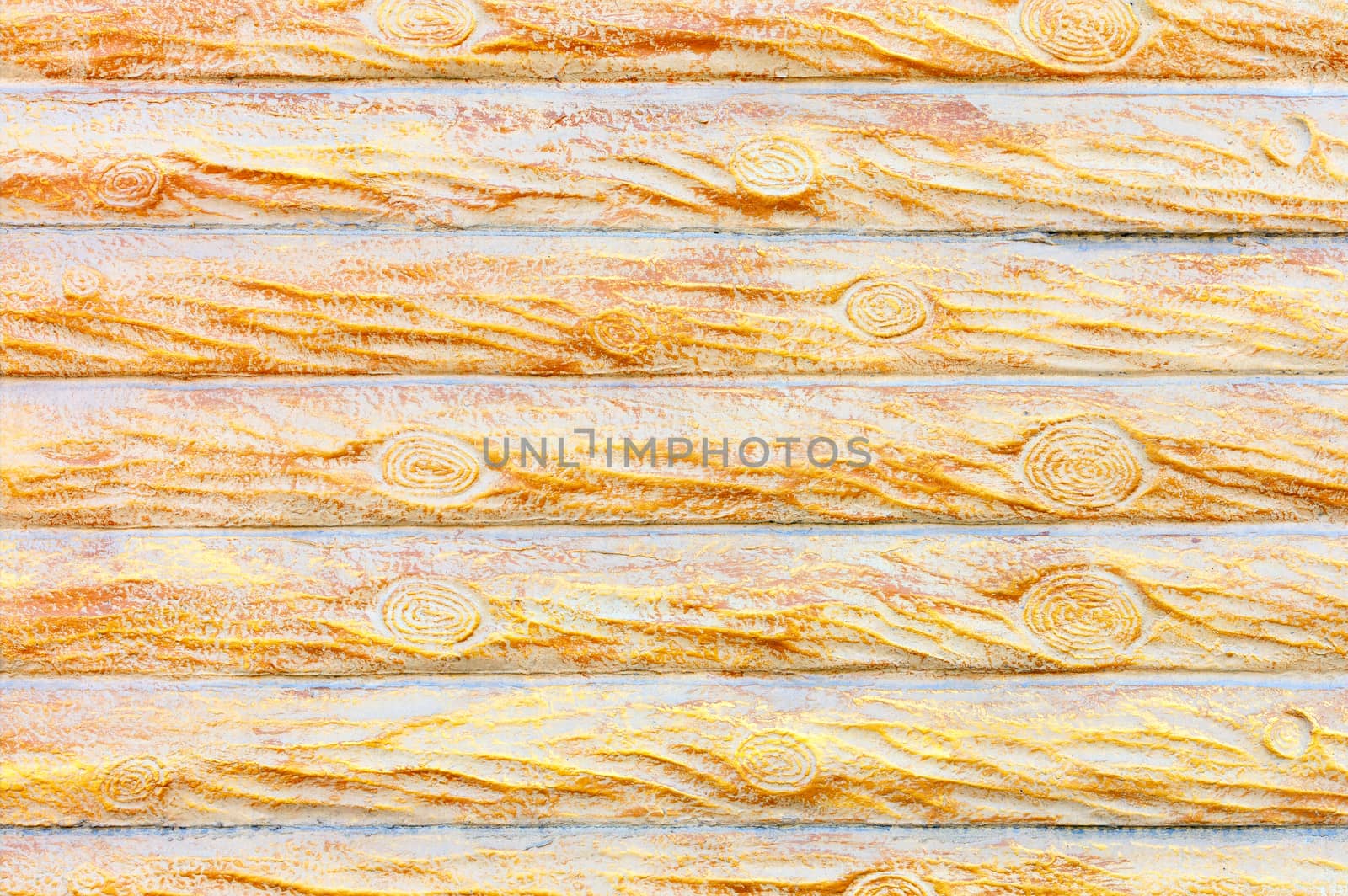 The texture and background of the concrete wall under a stylized wooden fence in the form of horizontal logs in yellow-gold color.