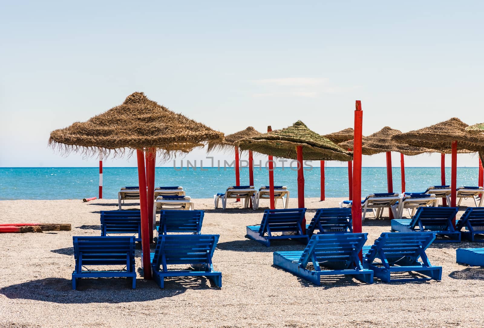 Lonely wicker sun umbrella with two hammocks on empty beach in Fuerteventura. Colorful turquoise sea water on sunny day in Caleta de Fuste, Canary Islands. Nobody enjoying summer holidays concept