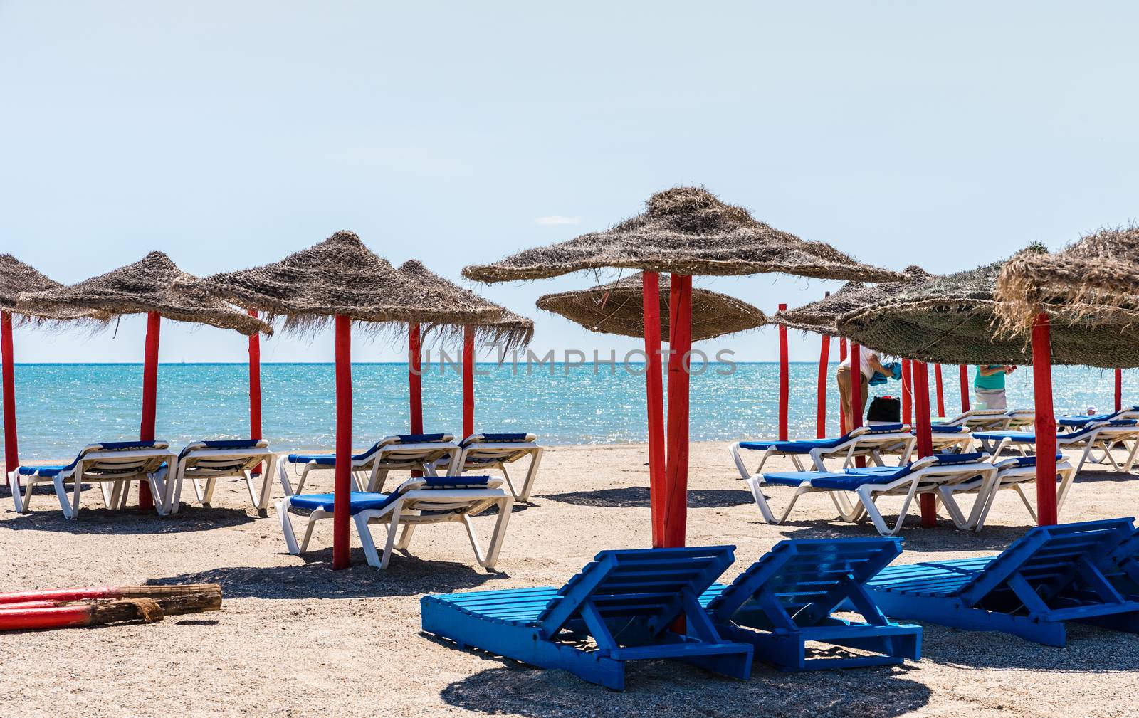 Lonely wicker sun umbrella with two hammocks on empty beach in Fuerteventura. Colorful turquoise sea water on sunny day in Caleta de Fuste, Canary Islands. Nobody enjoying summer holidays concept