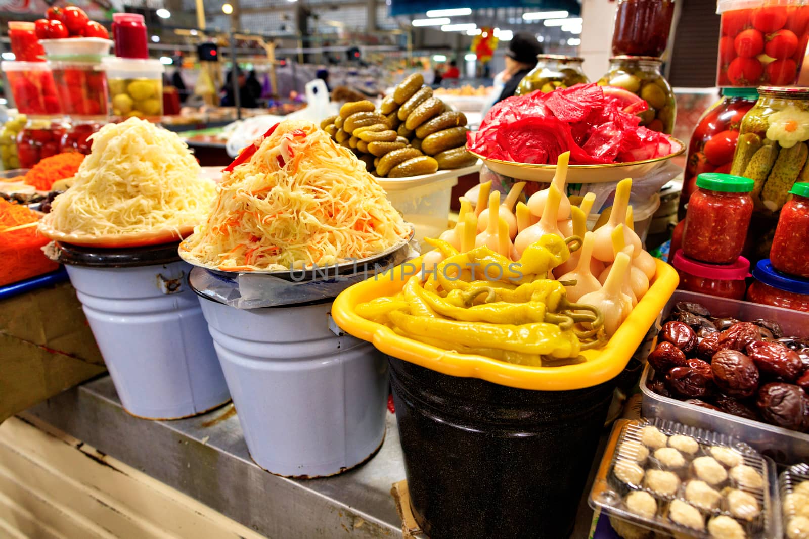 Pickled vegetables in buckets and glass jars on a market counter. Cauliflower, pepper, chapel, cucumbers, tomatoes, carrots. Fermented product. Diversity. Copy space.