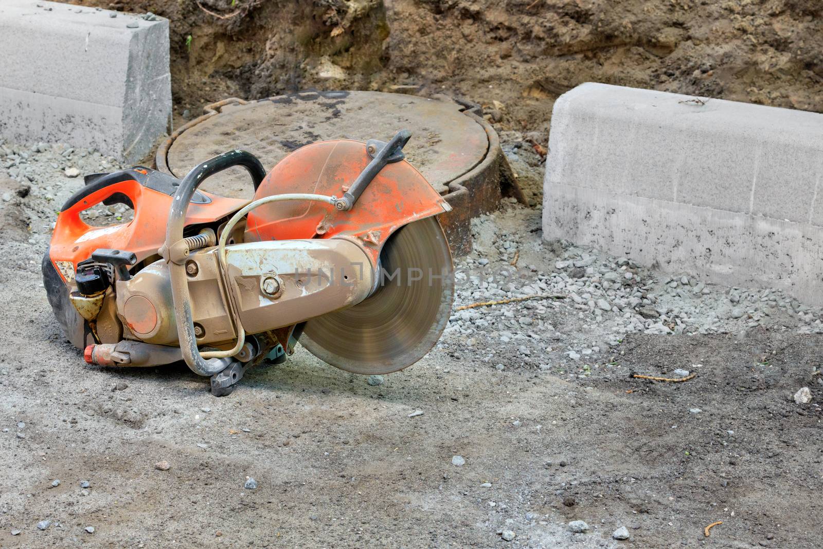 Concrete cutter at a construction site with a running engine and a diamond blade for cutting concrete, copy space.