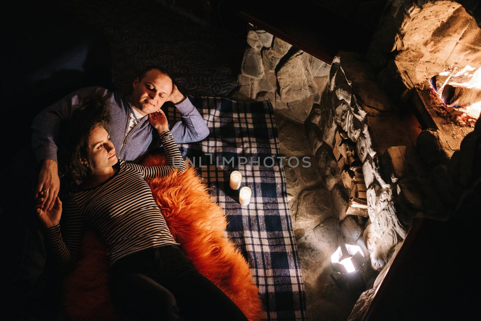 guy and girl are sitting on the background of a burning fireplac by Andreua