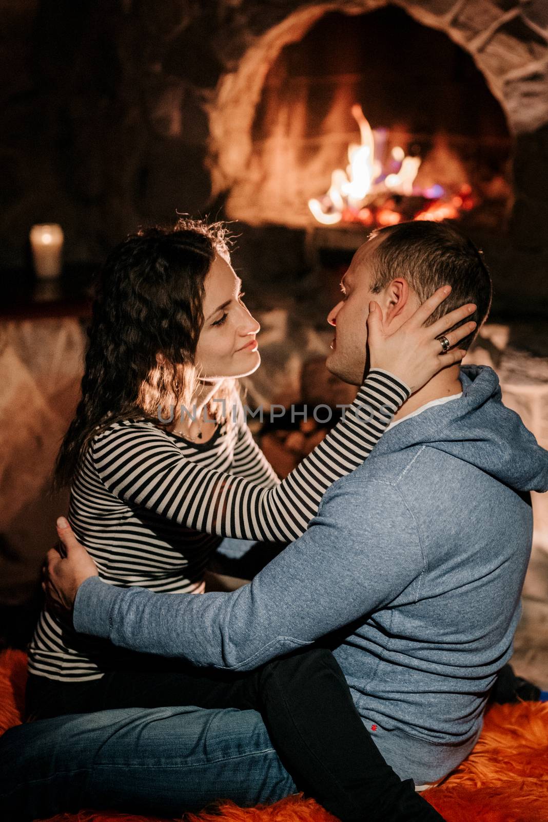 guy and girl are sitting on the background of a burning fireplac by Andreua