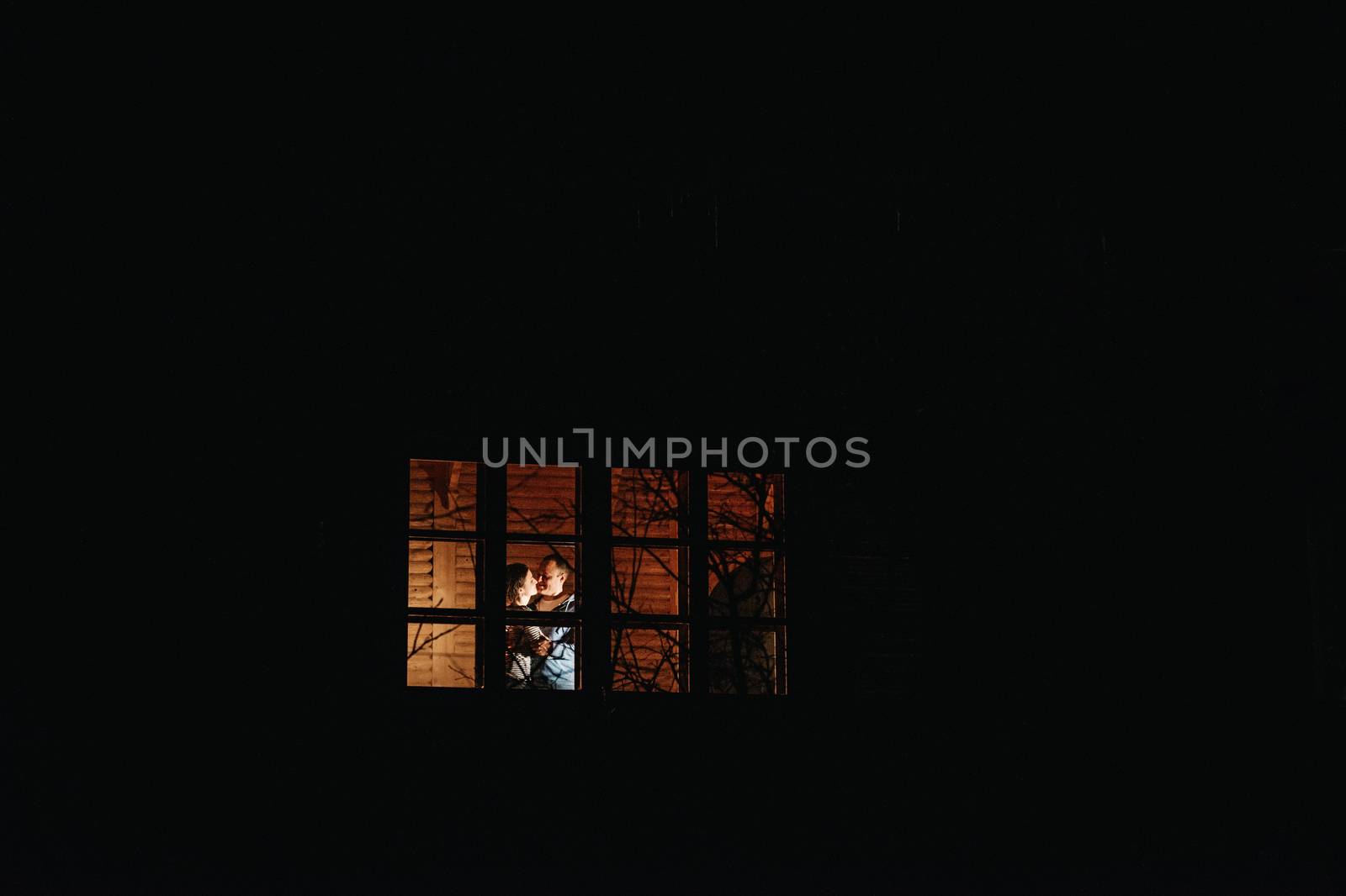 guy and girl are sitting in a wooden house on the background of a burning fireplace