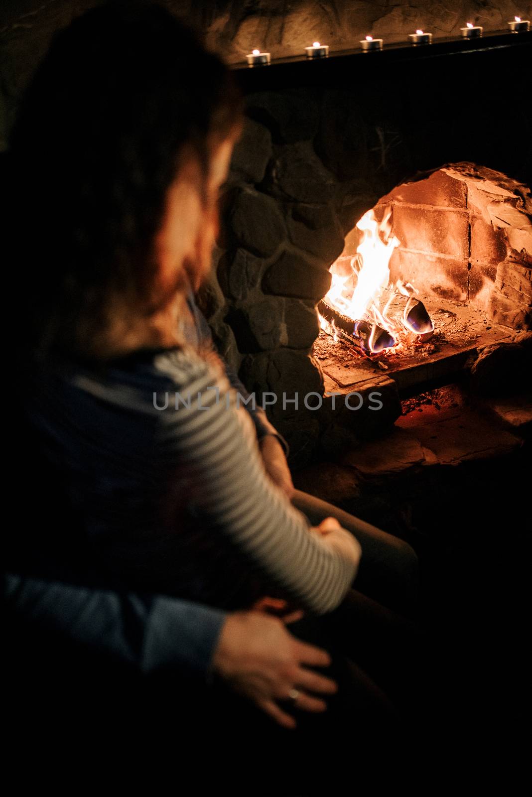 guy and girl are sitting in a wooden house on the background of a burning fireplace