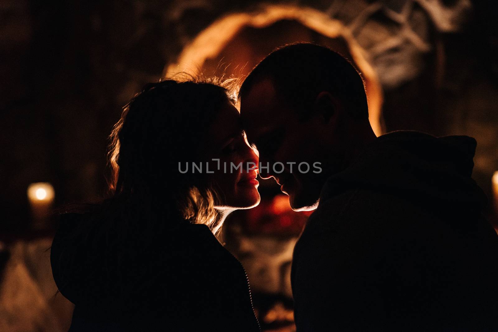 guy and girl are sitting in a wooden house on the background of a burning fireplace