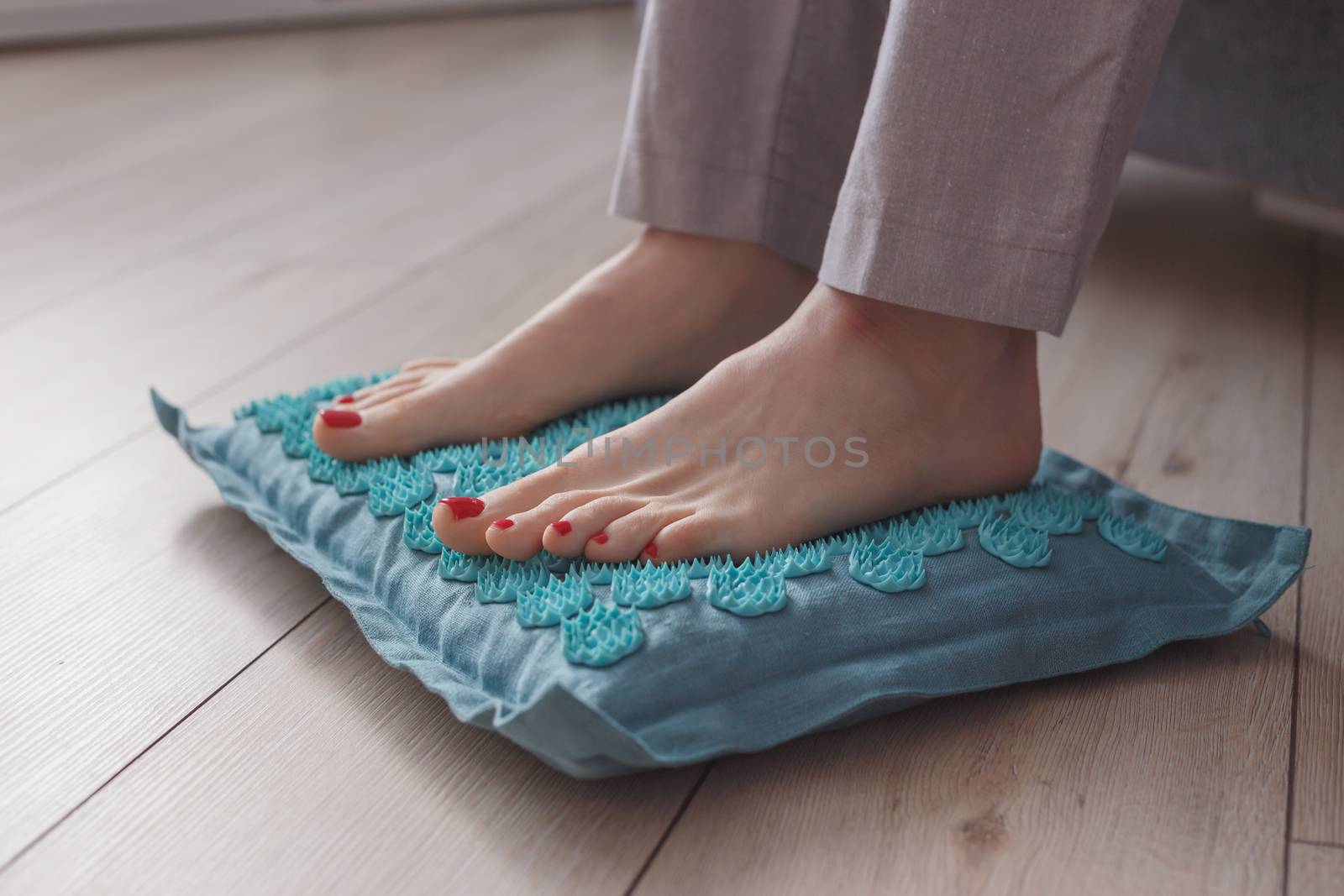 Female feet standing on acupressure mat. Self acupuncture massage. Woman having alternative medicine treatment. by vladdeep