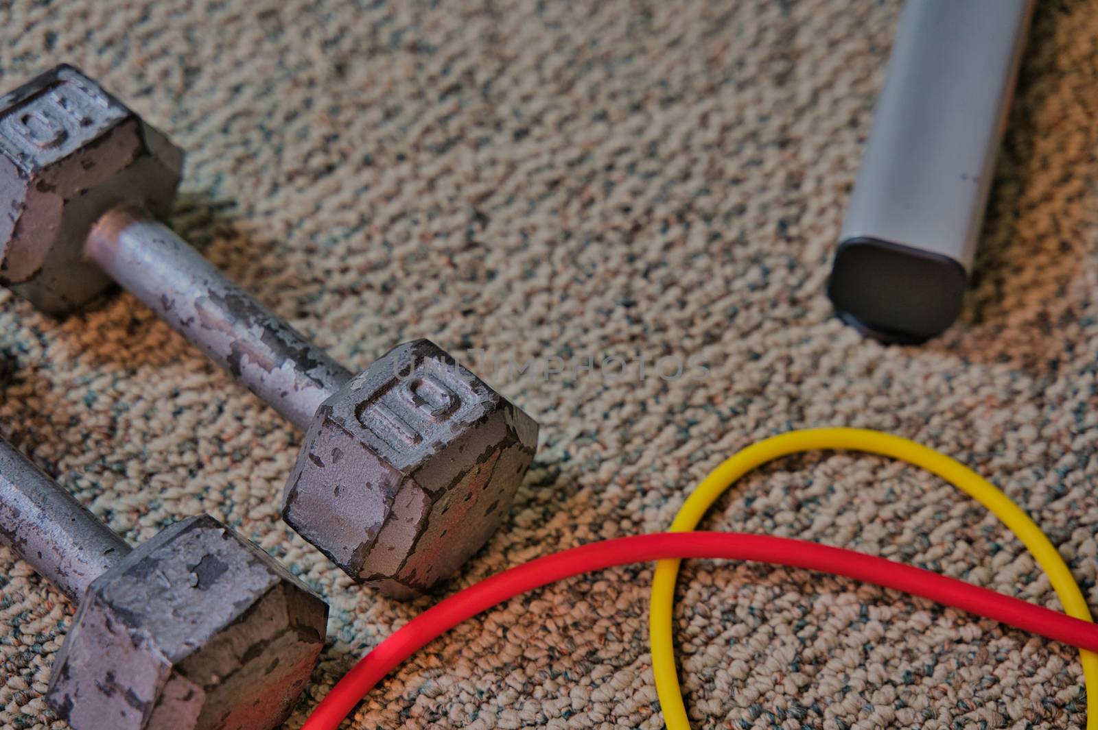 Exercise equipment sitting on carpeted floor of home gym in basement. Workout equipment flat lay with open space