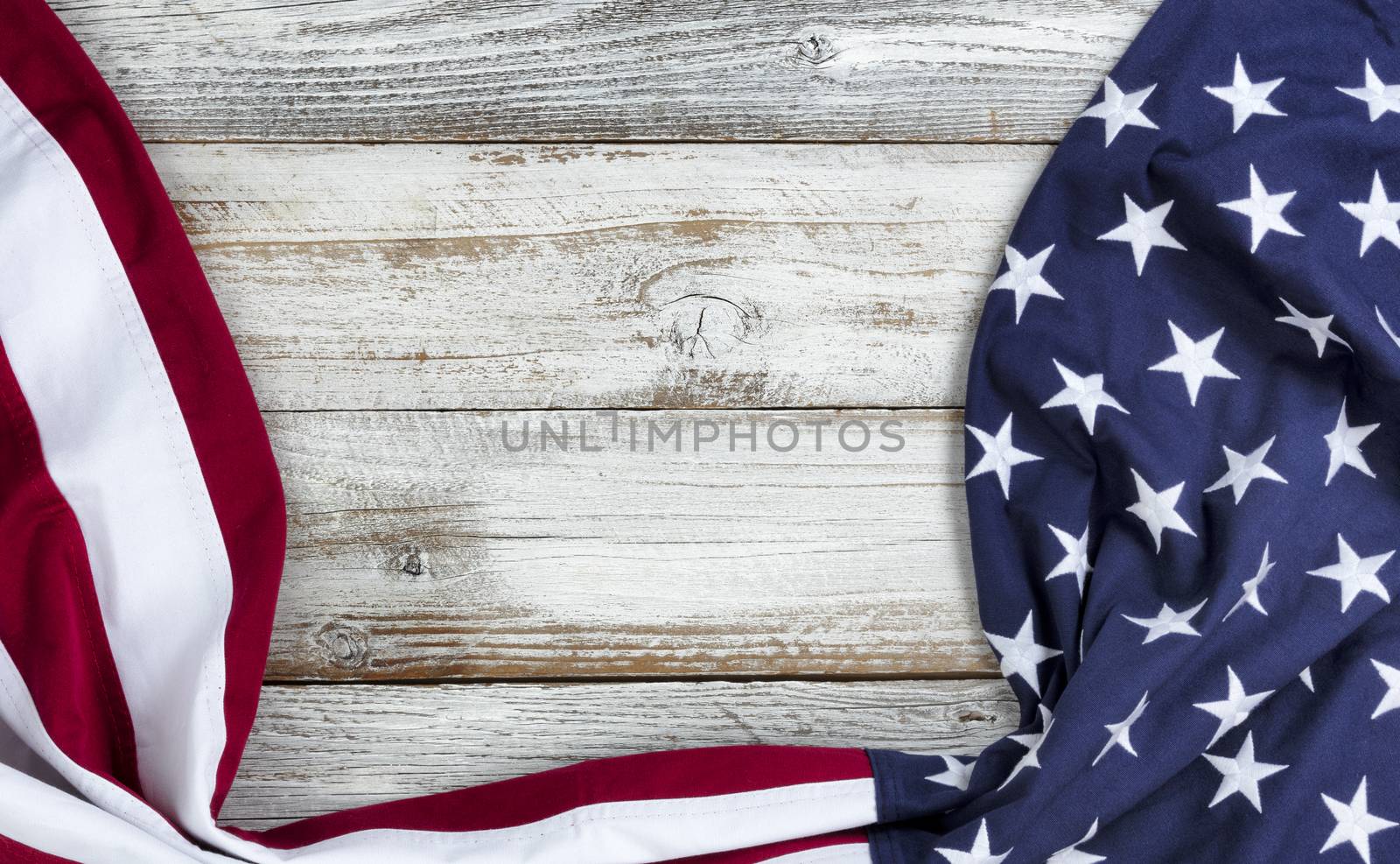 Draping United States flag on bottom and side borders of white rustic wooden background 