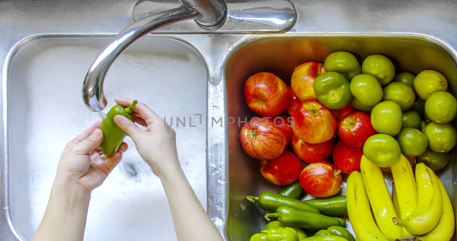 Washing vegetables and fruits on a sing with running water and soap